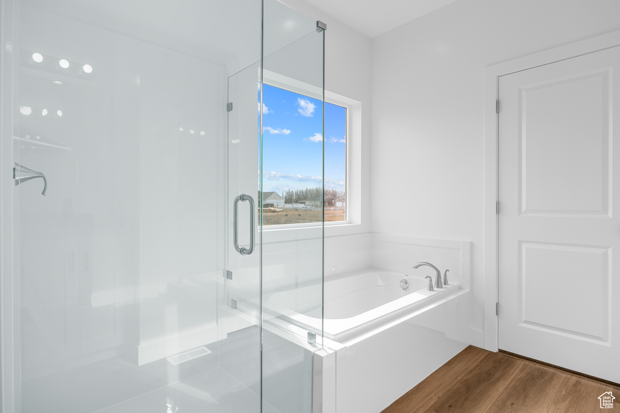 Bathroom featuring a shower stall, a bath, and wood finished floors