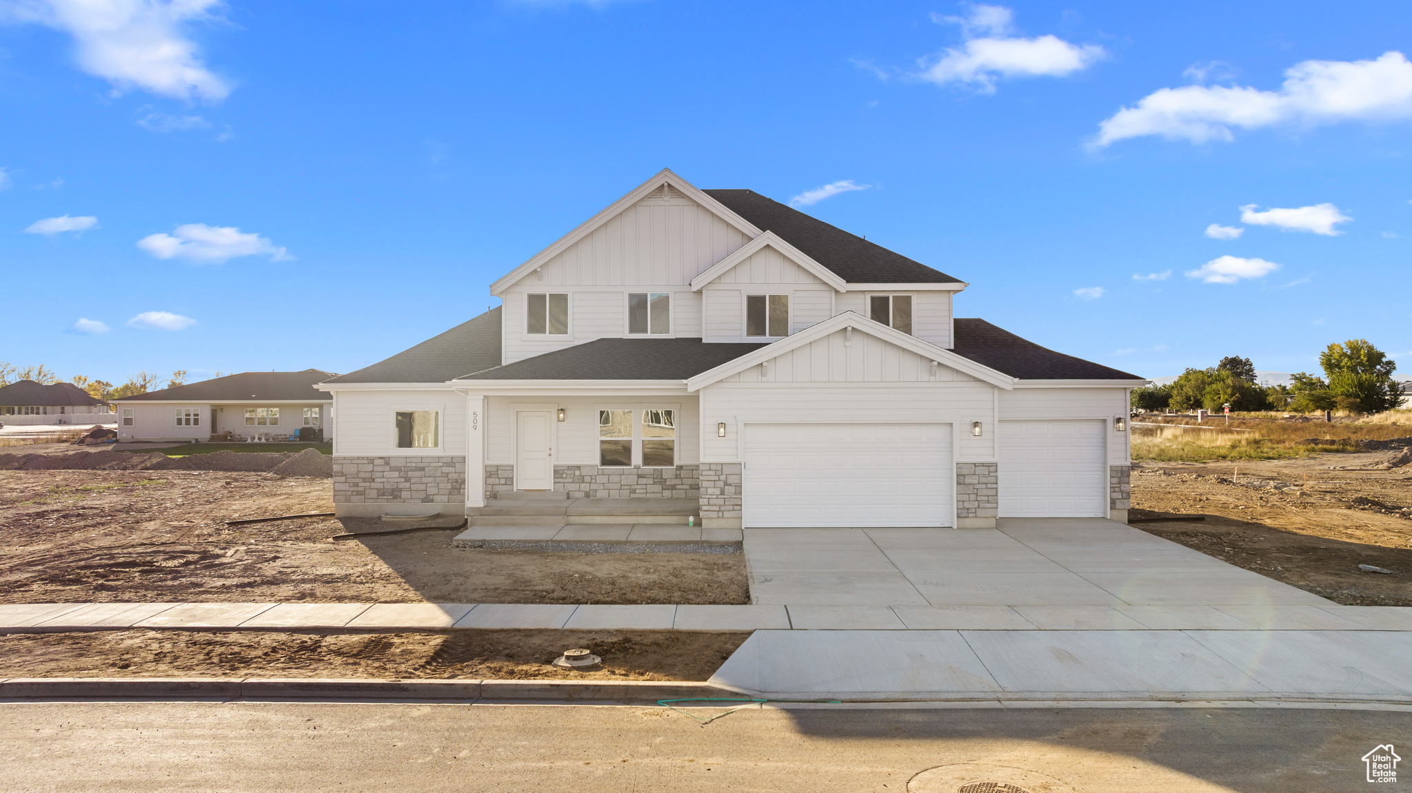 View of front of house with stone siding, concrete driveway, board and batten siding, and an attached garage