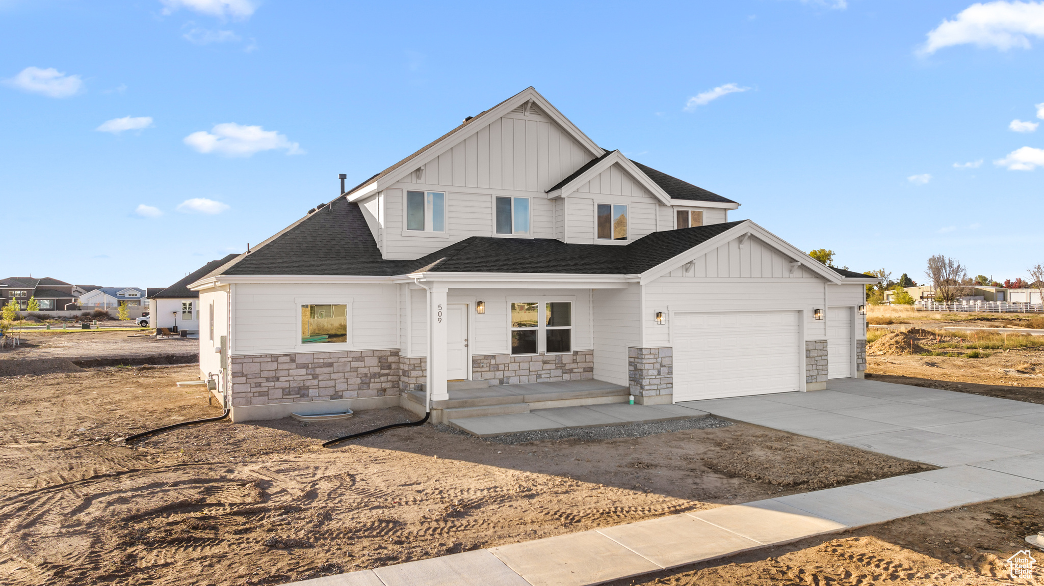 Modern farmhouse style home with a garage, stone siding, board and batten siding, and concrete driveway