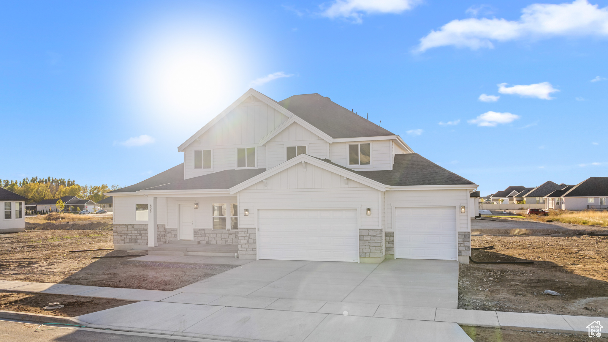 View of front of home featuring driveway, stone siding, an attached garage, and board and batten siding