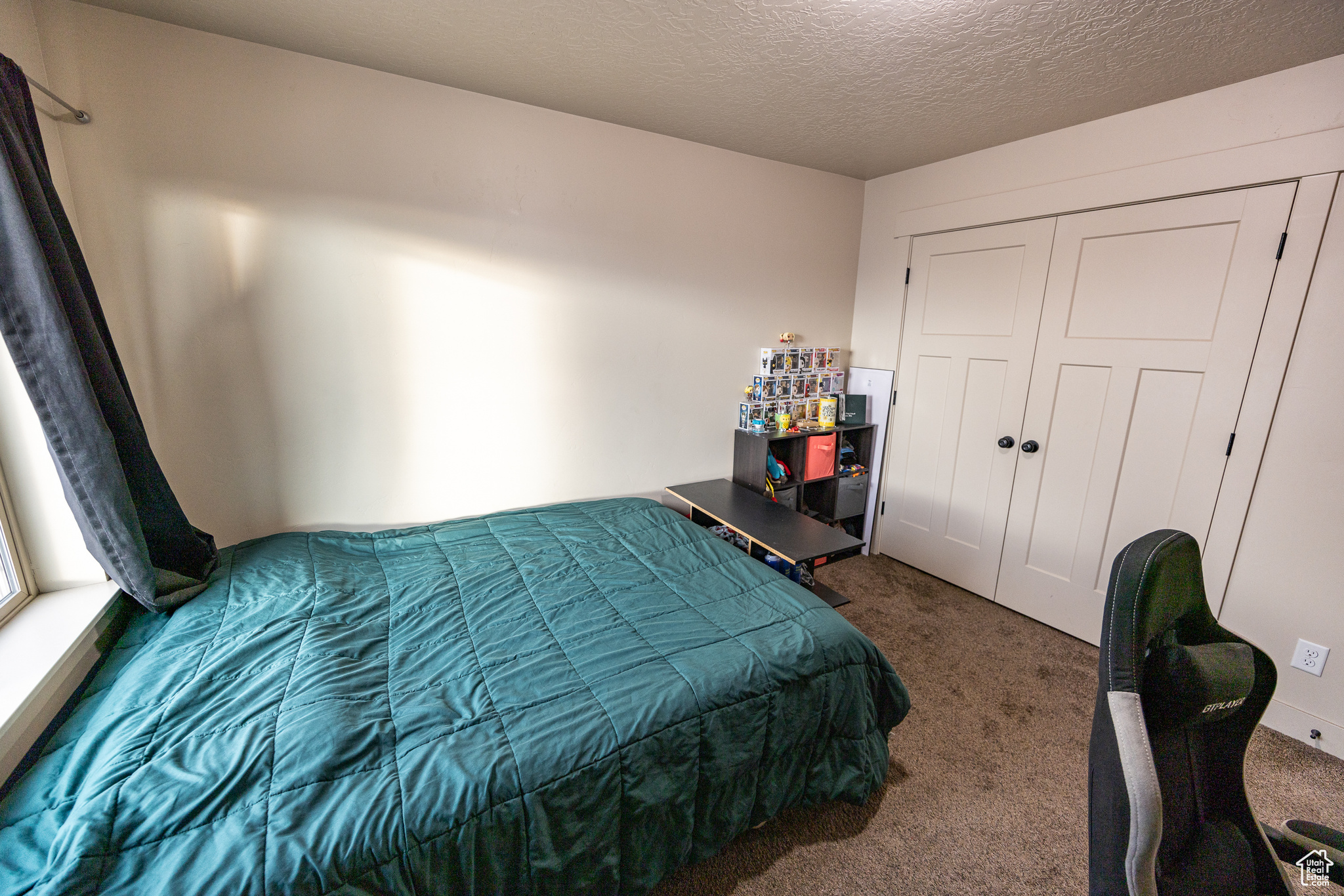 Carpeted bedroom featuring a closet and a textured ceiling