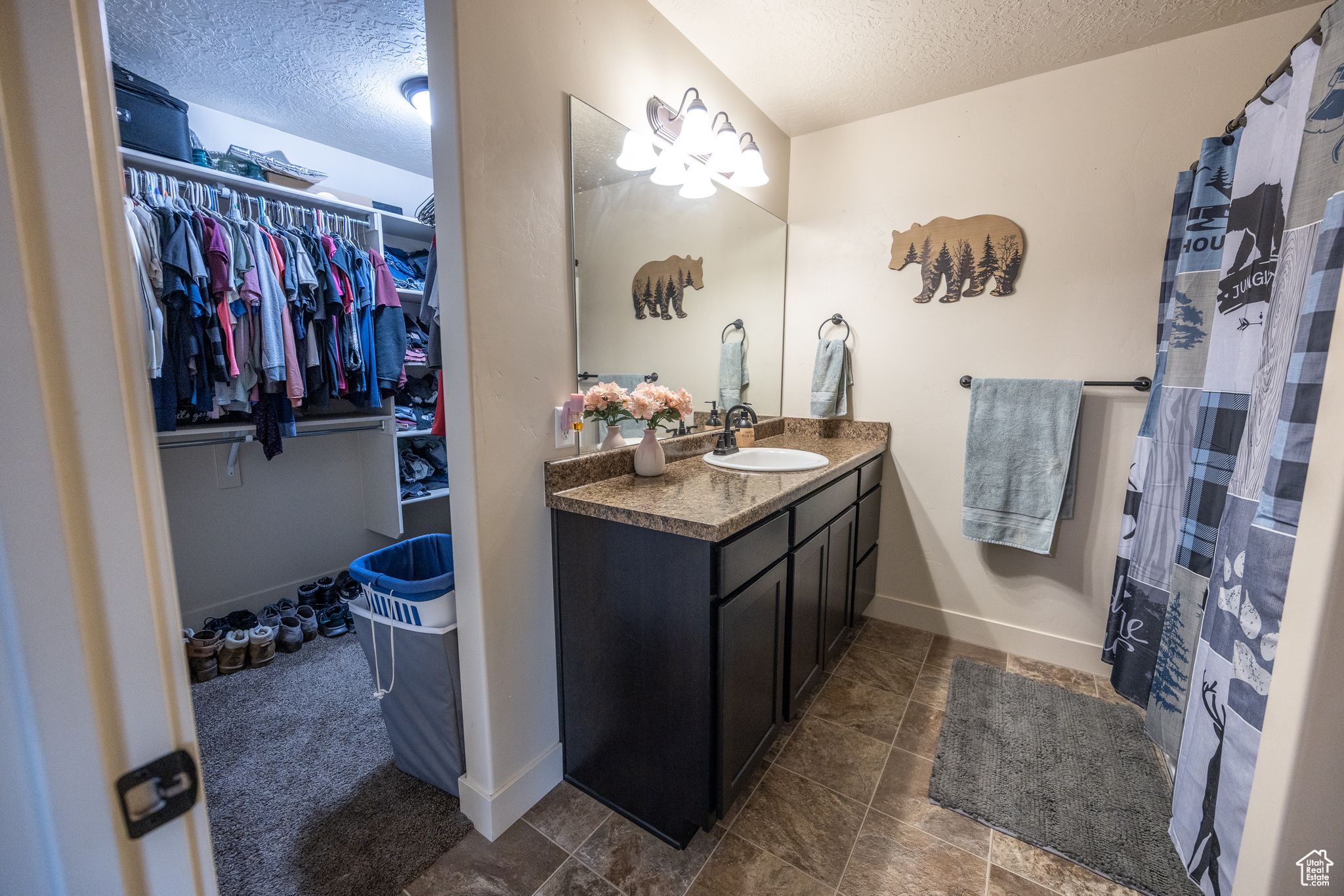 Full bath featuring a walk in closet, baseboards, a textured ceiling, and vanity