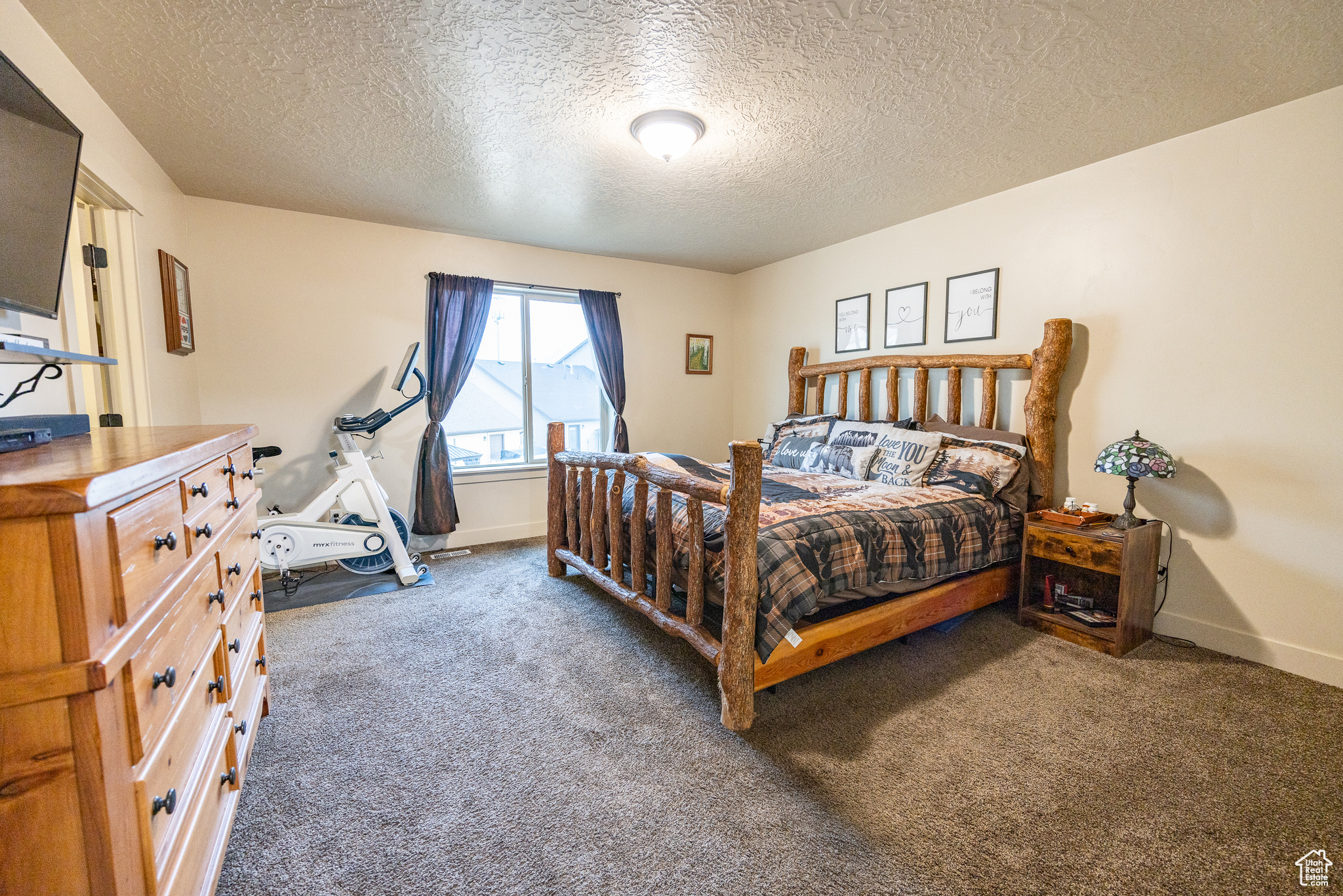 Bedroom with a textured ceiling, dark carpet, and baseboards