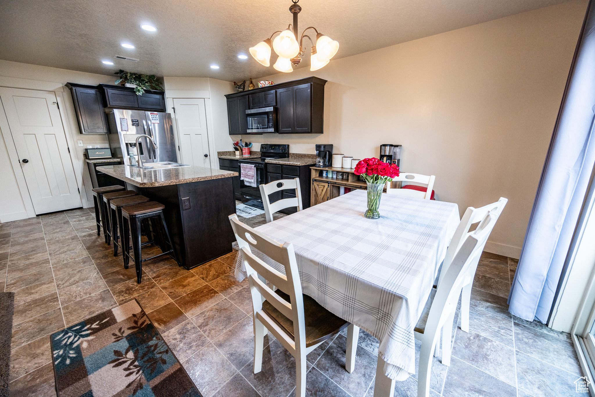 Dining area with baseboards, stone finish floor, an inviting chandelier, a textured ceiling, and recessed lighting