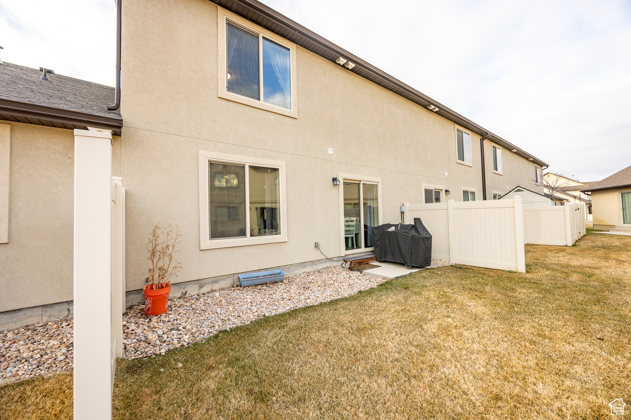 Back of house with a yard, fence, and stucco siding