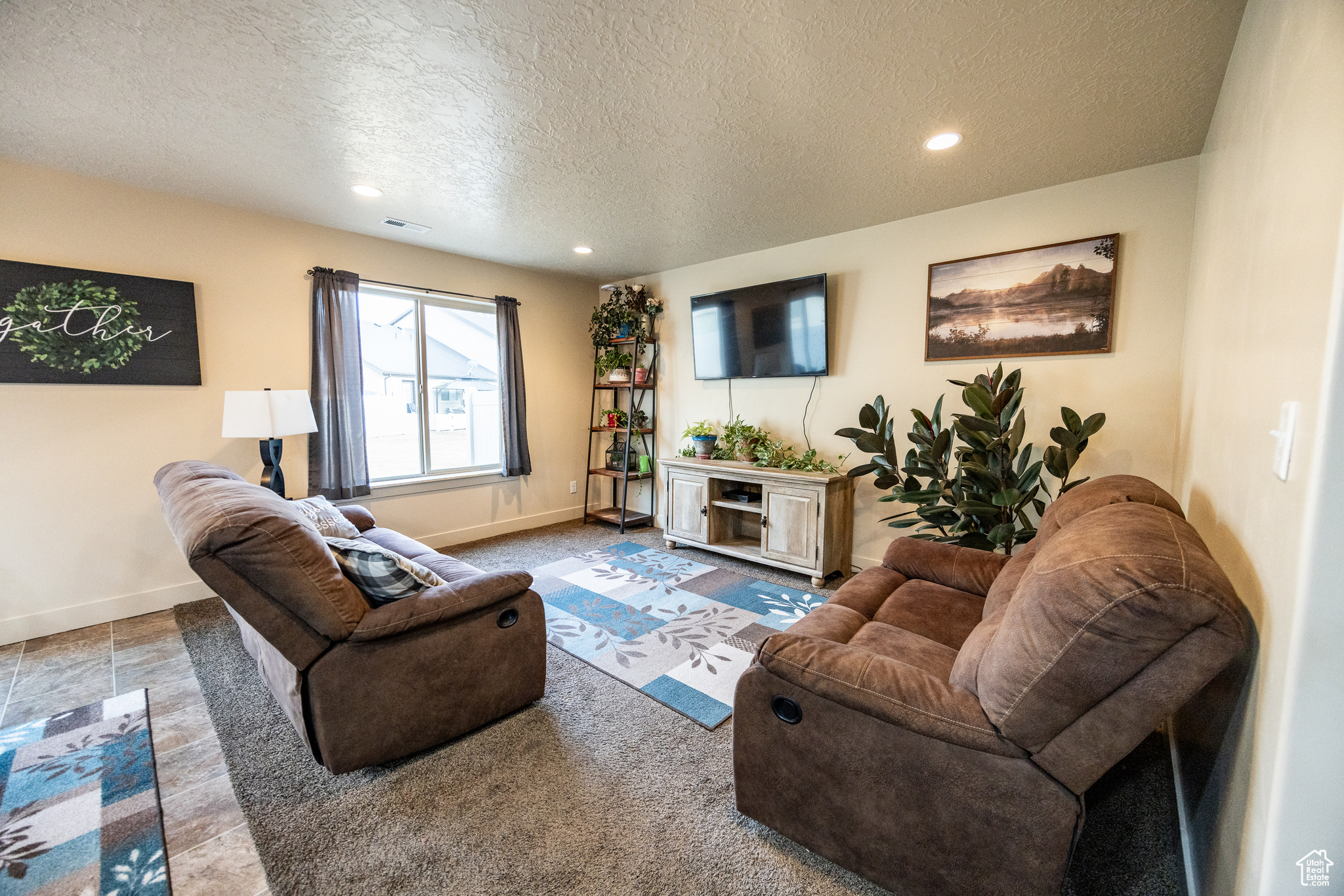 Living room with baseboards, visible vents, a textured ceiling, and recessed lighting