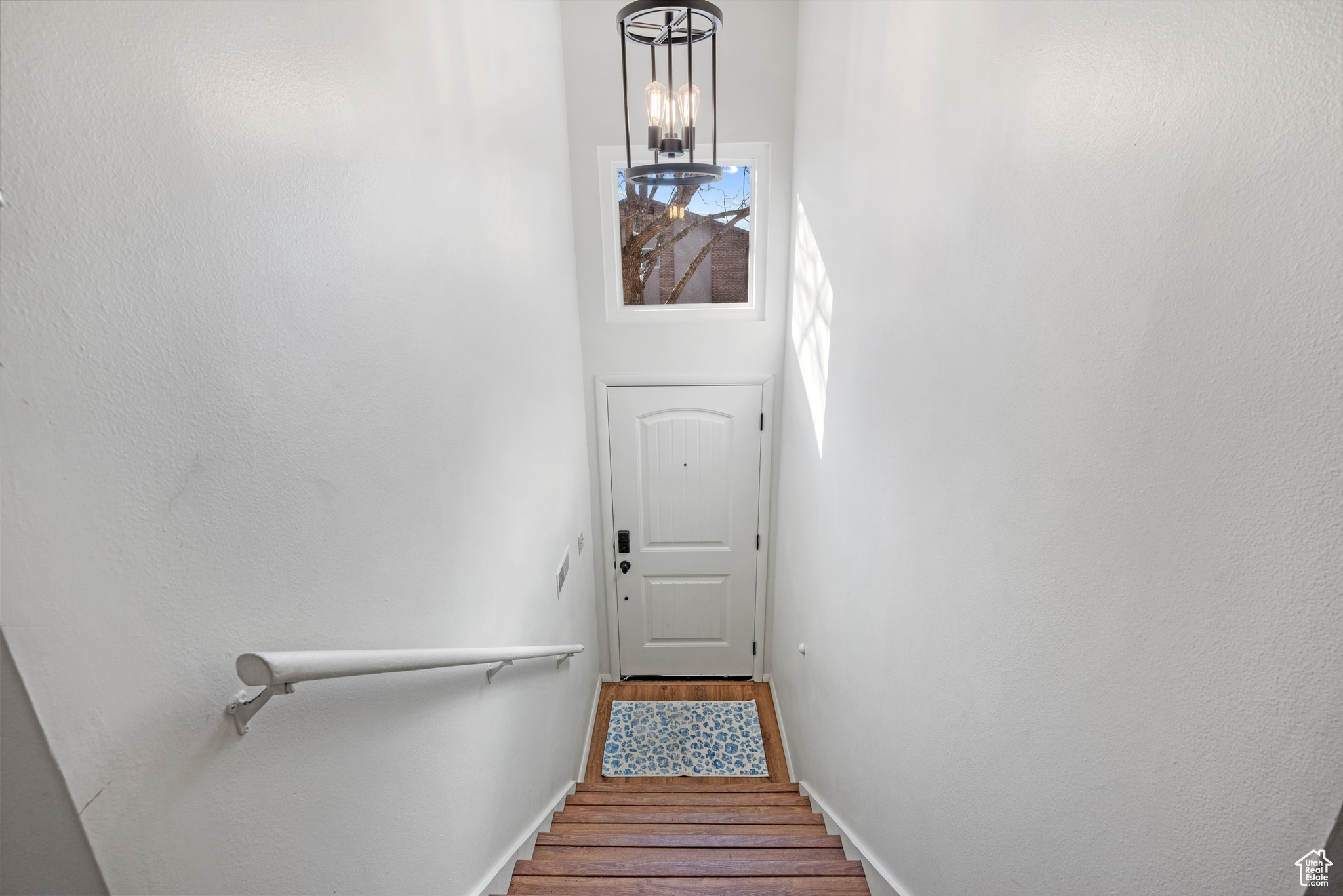 Stairway featuring hardwood / wood-style flooring, a chandelier, and a high ceiling