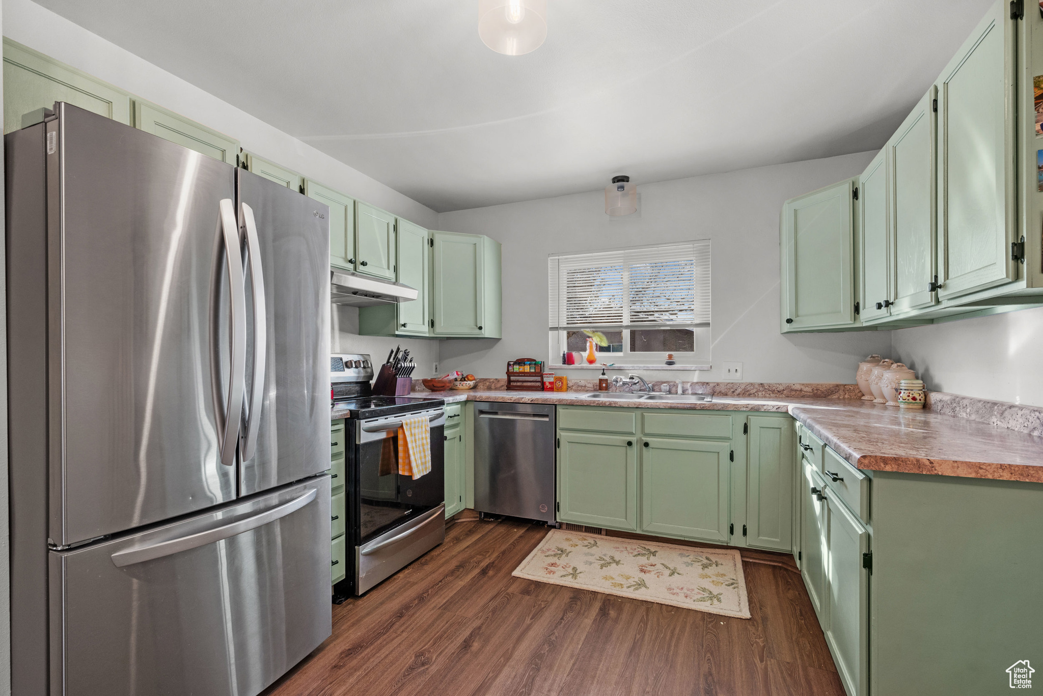 Kitchen featuring sink, stainless steel appliances, dark hardwood / wood-style floors, and green cabinets