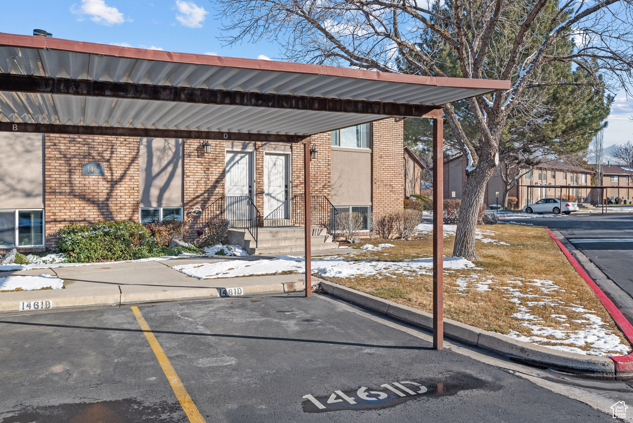 Snow covered parking area featuring a carport