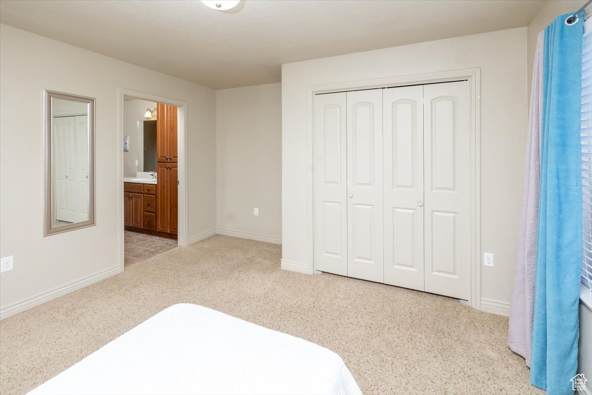 Bedroom with a closet, ensuite bathroom, and light colored carpet