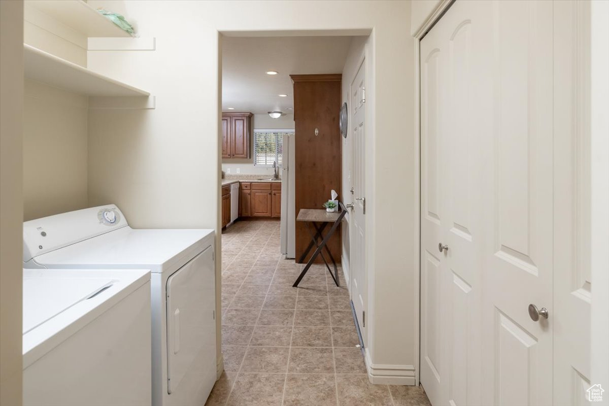 Clothes washing area with light tile patterned flooring and independent washer and dryer