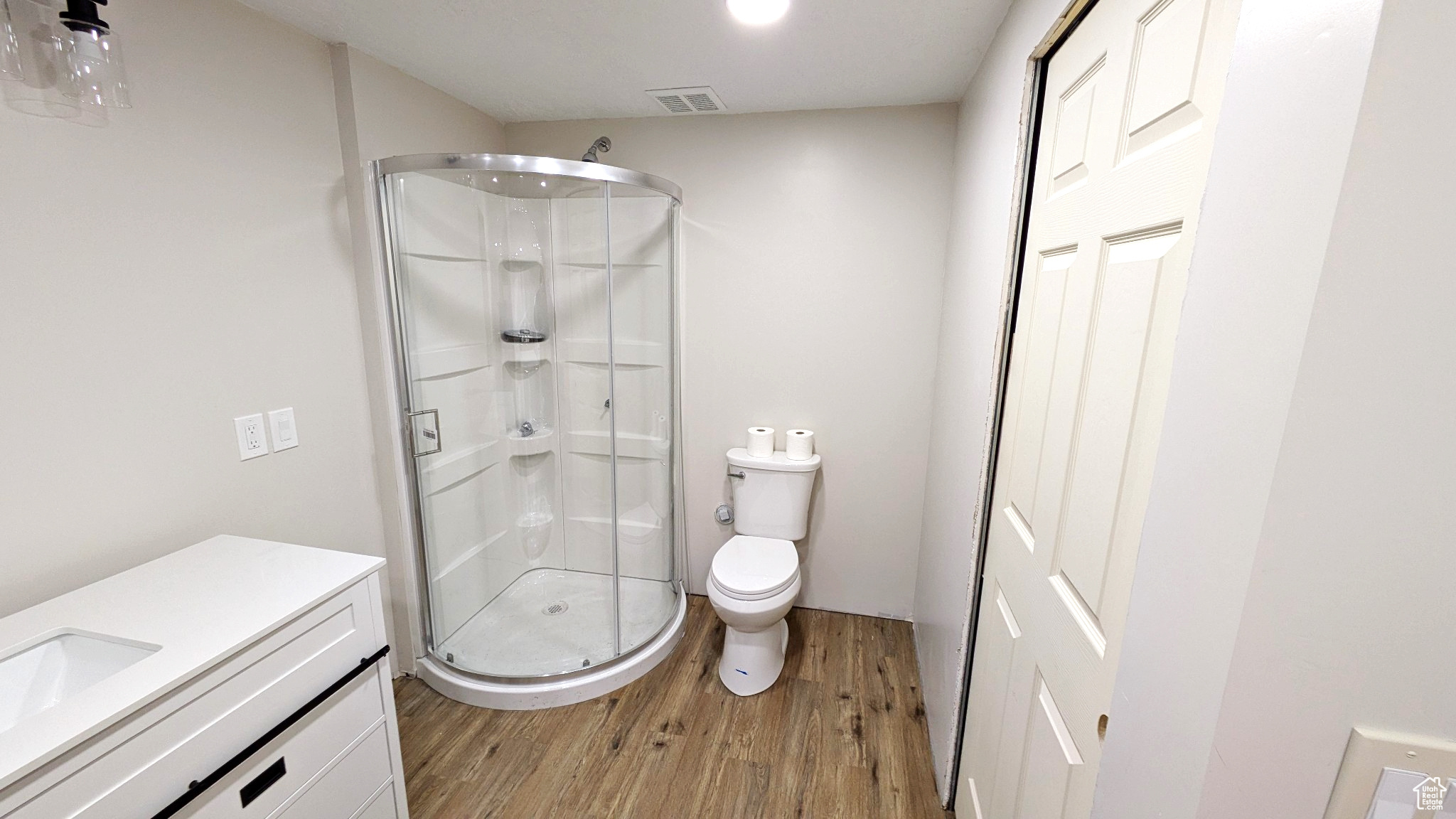 Bathroom featuring vanity, hardwood / wood-style flooring, toilet, and an enclosed shower