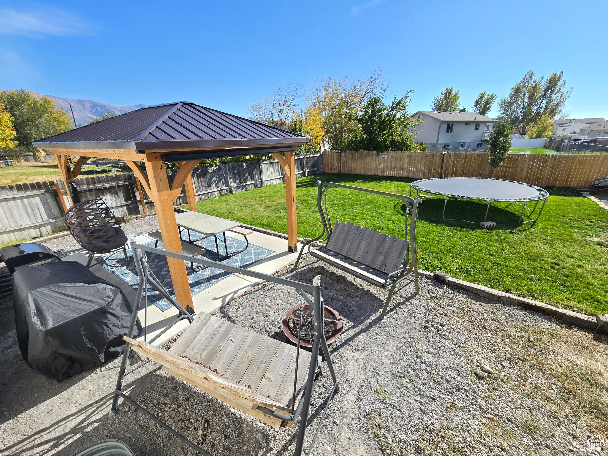 Deck featuring a mountain view, a trampoline, a lawn, a gazebo, and a patio