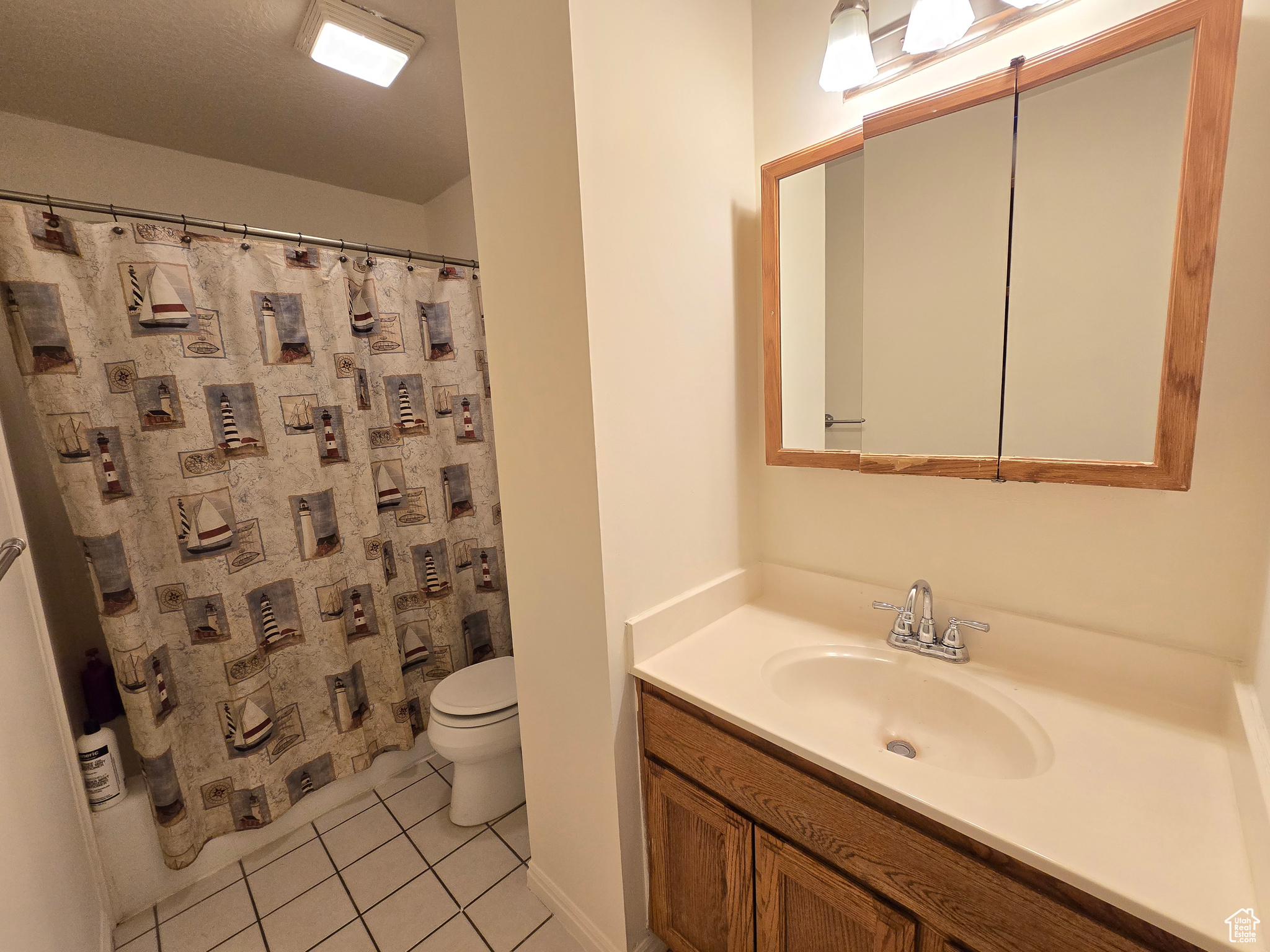 Bathroom with vanity, a shower with curtain, toilet, and tile patterned flooring