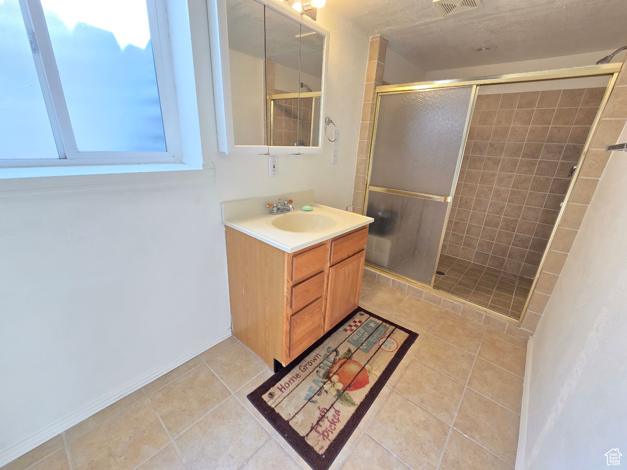 Bathroom featuring vanity, a shower with shower door, and tile patterned floors