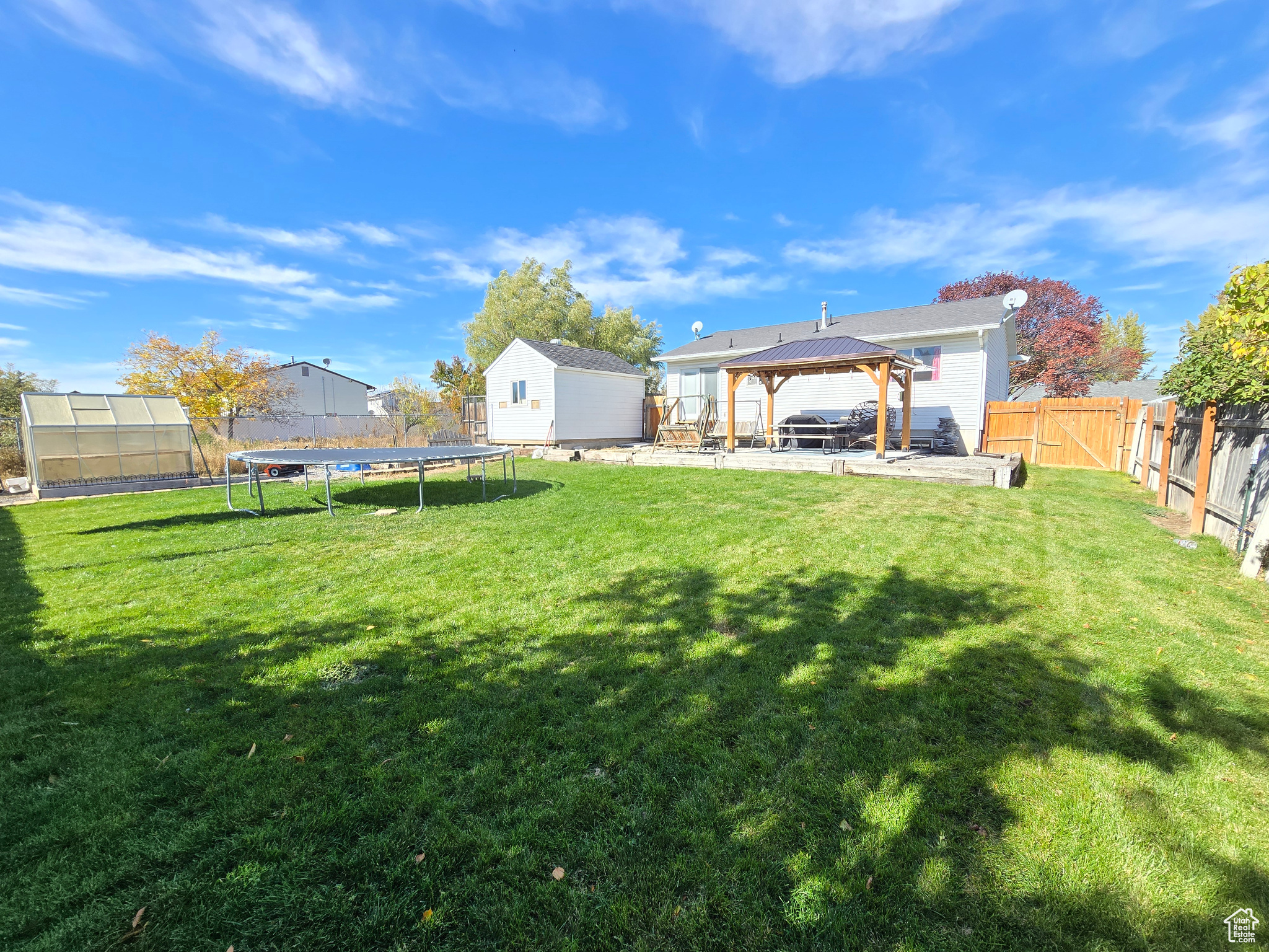 View of yard with a gazebo, a storage unit, a trampoline, and a patio area