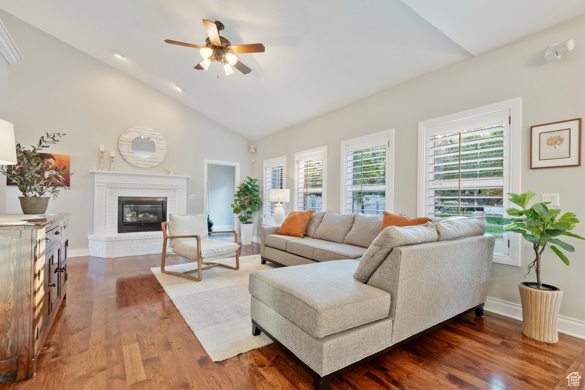 Living room featuring ceiling fan, high vaulted ceiling, dark hardwood / wood-style flooring, and a fireplace