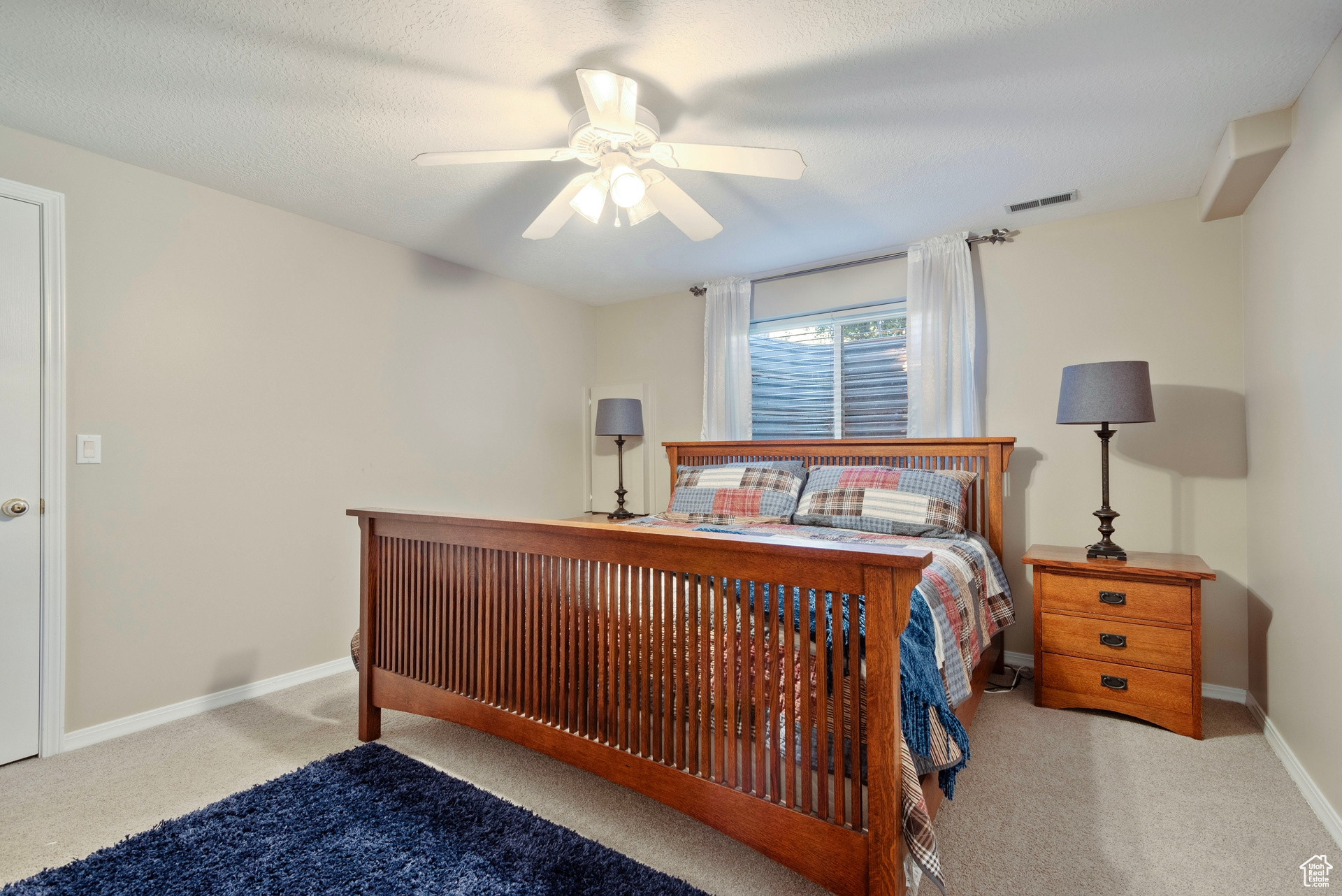 Carpeted bedroom featuring a textured ceiling and ceiling fan