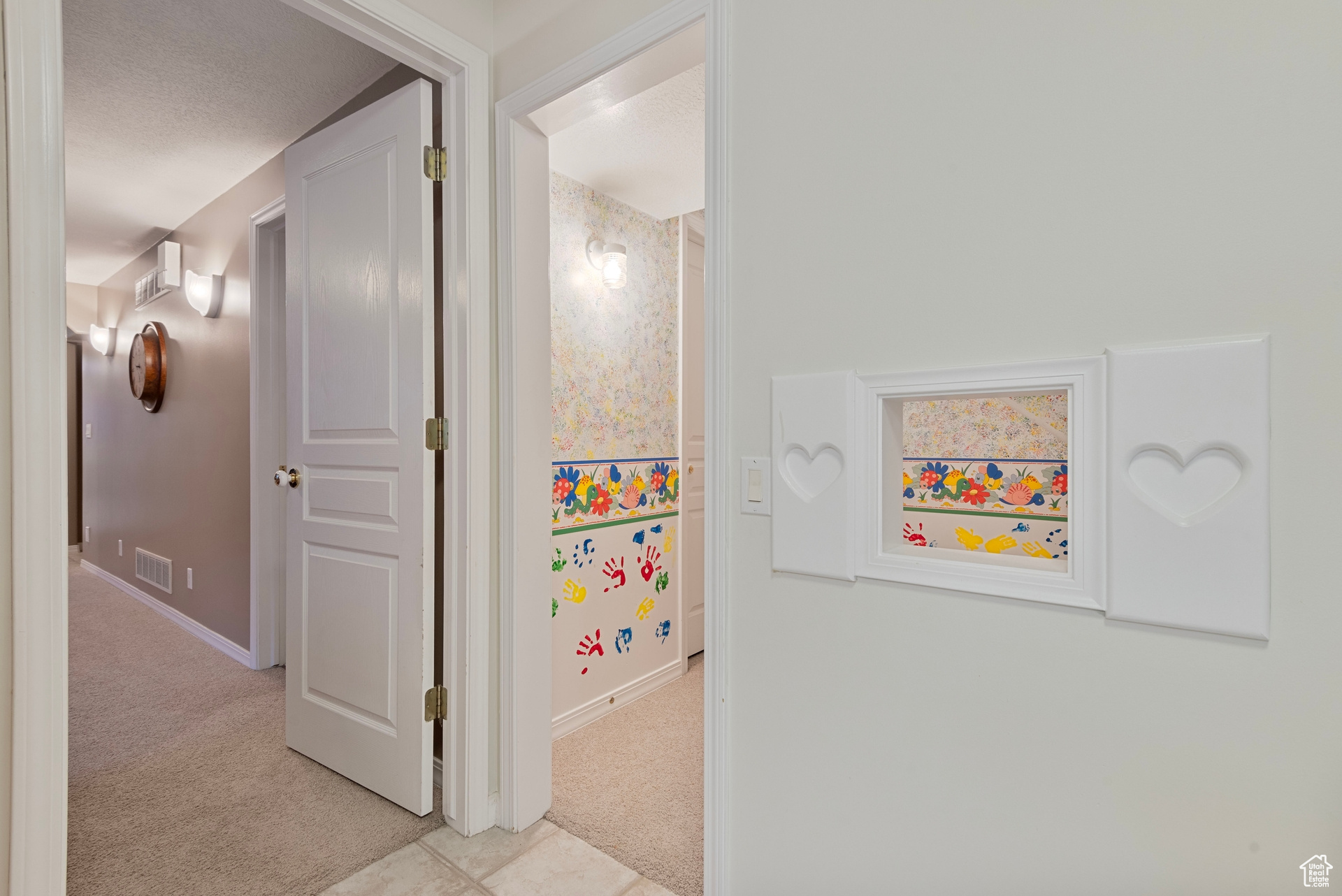 Corridor featuring a textured ceiling and light colored carpet