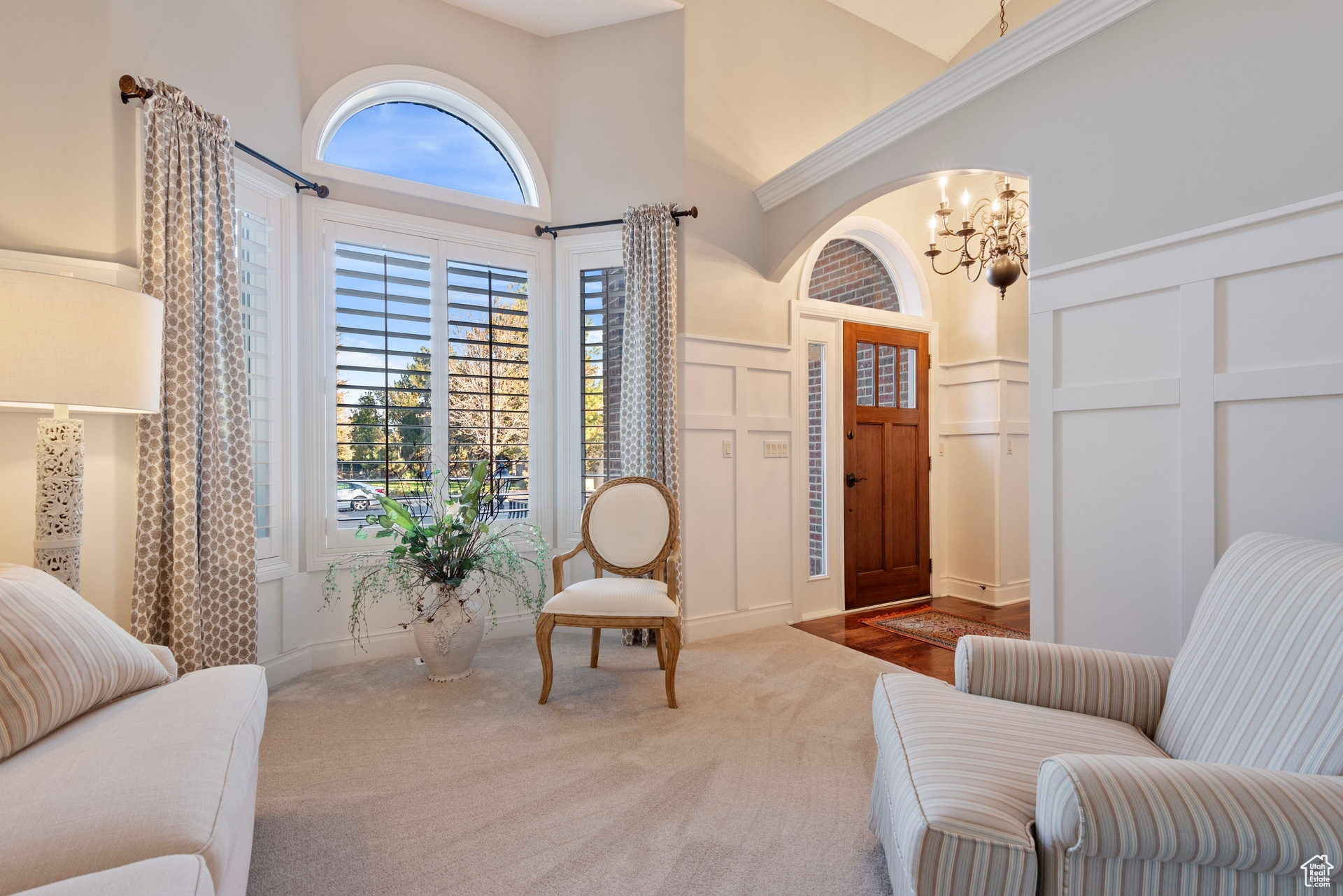 Living area featuring a notable chandelier, carpet flooring, and high vaulted ceiling