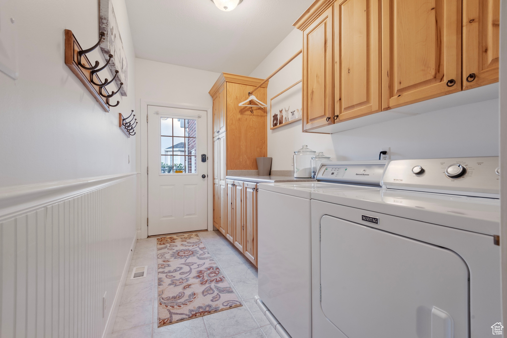 Laundry room featuring light tile patterned flooring, washing machine and dryer, and cabinets