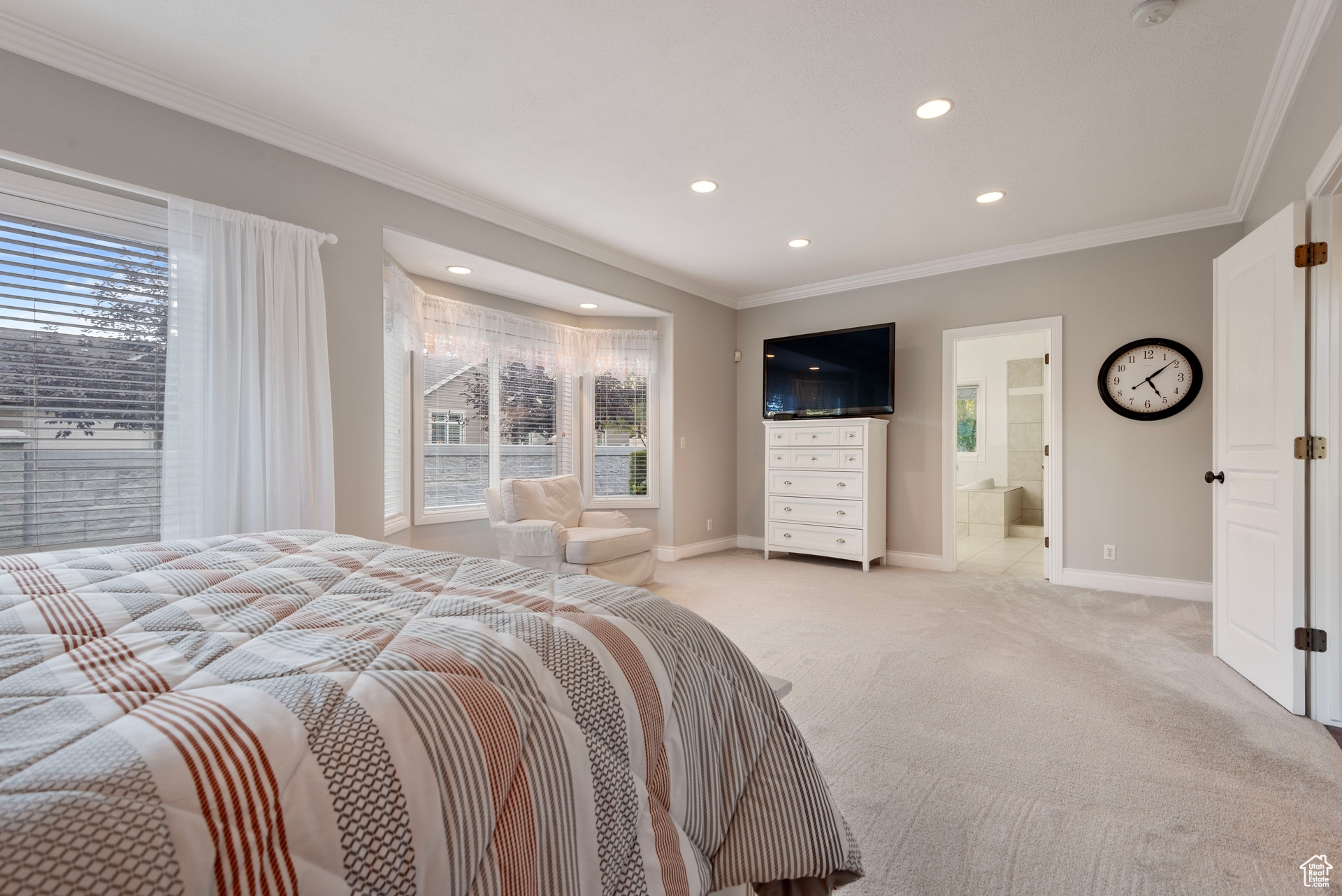 Bedroom with light carpet, ornamental molding, and connected bathroom