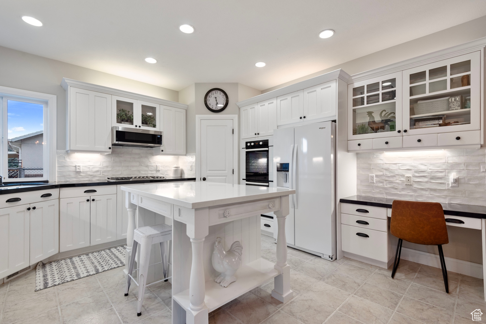 Kitchen featuring a center island, stainless steel appliances, white cabinets, decorative backsplash, and a breakfast bar area