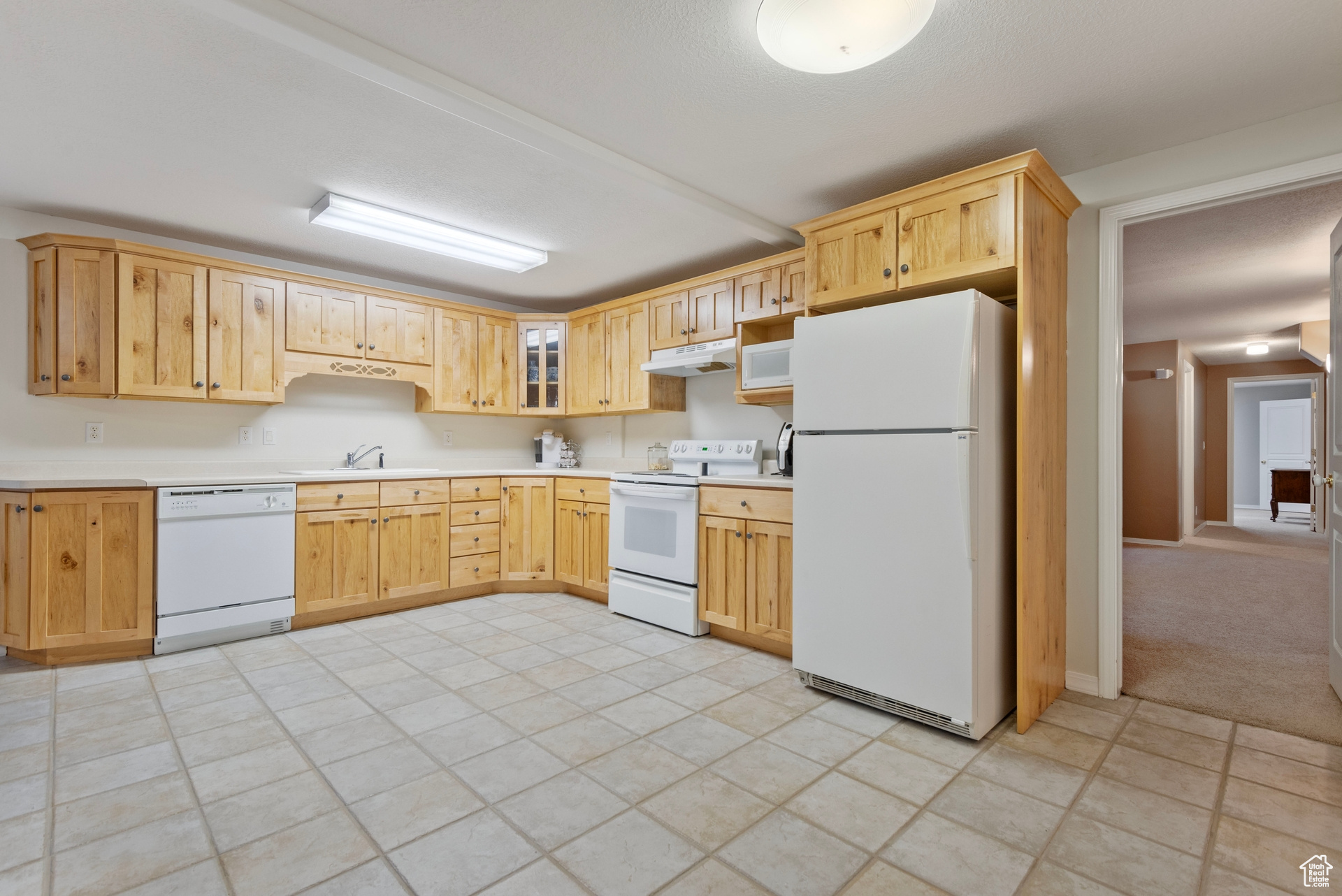 Kitchen featuring sink, white appliances, and light tile patterned floors