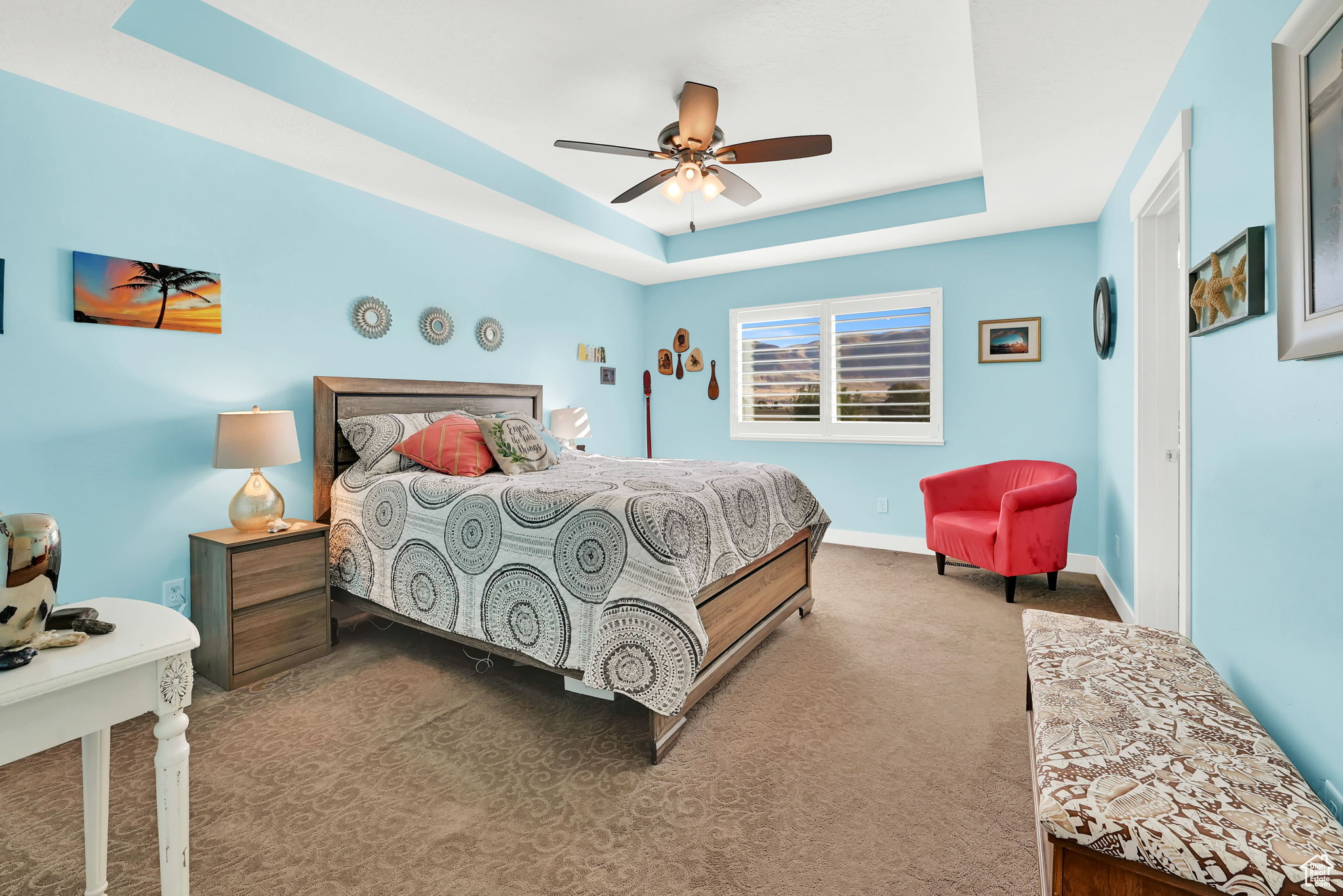 Carpeted bedroom featuring a raised ceiling and ceiling fan