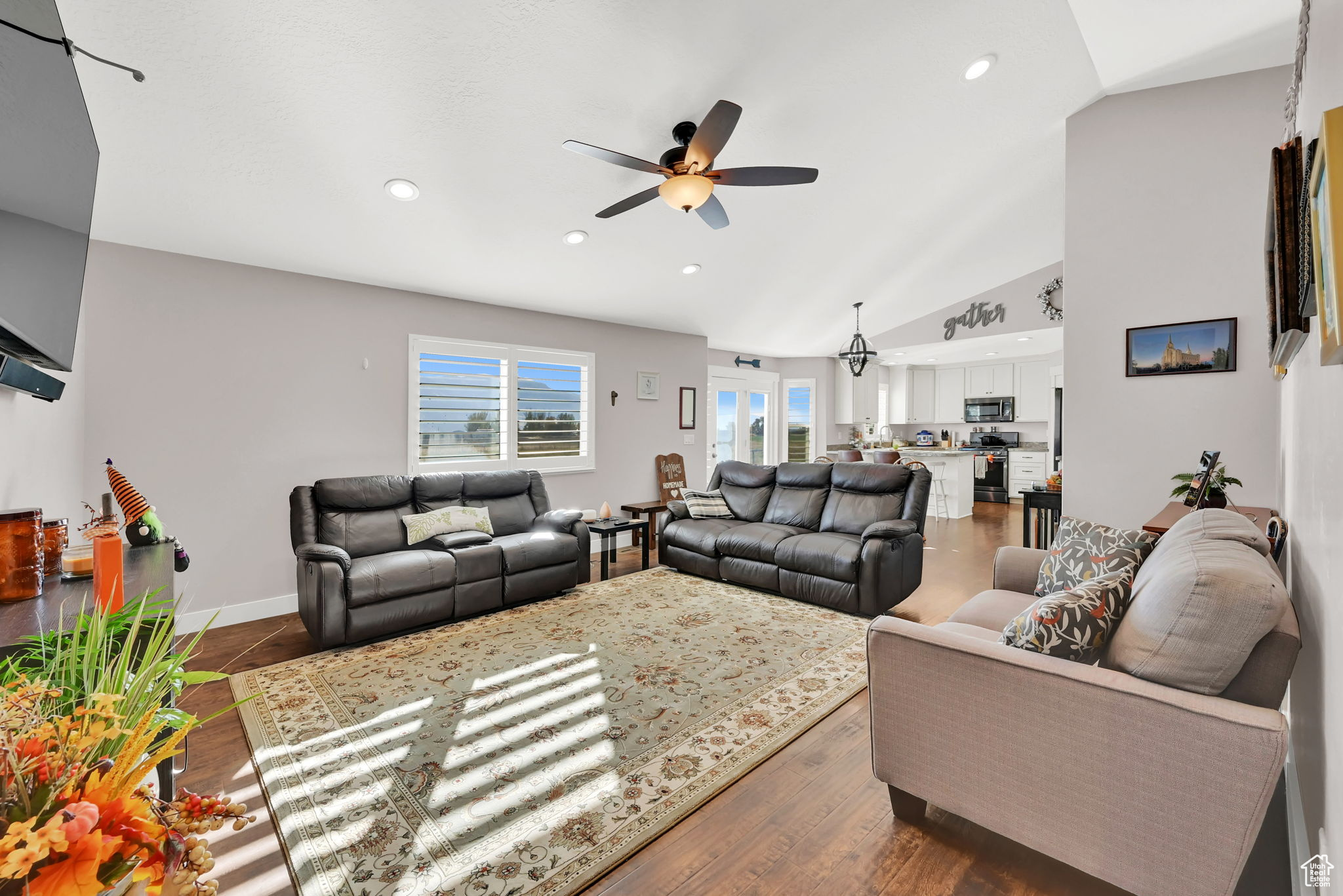 Living room featuring dark wood-type flooring, ceiling fan, and vaulted ceiling