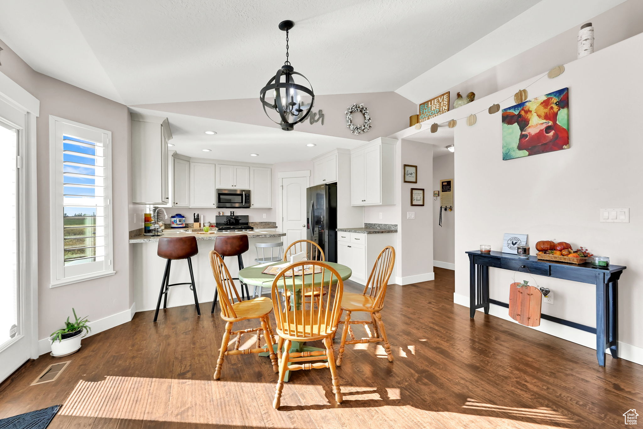 Dining space with dark wood-type flooring, vaulted ceiling, and a chandelier