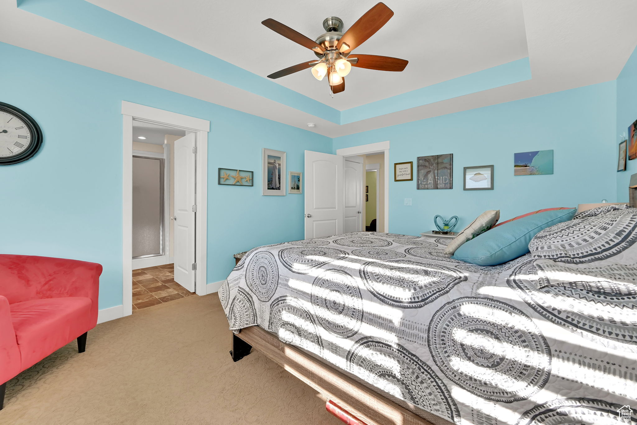 Bedroom featuring light carpet, a tray ceiling, and ceiling fan