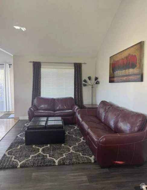 Living room with lofted ceiling and dark hardwood / wood-style floors