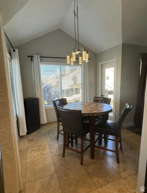 Tiled dining space with lofted ceiling and a chandelier