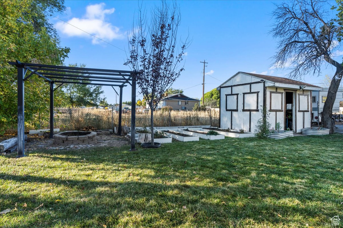 View of yard featuring a shed, a fire pit, and a pergola