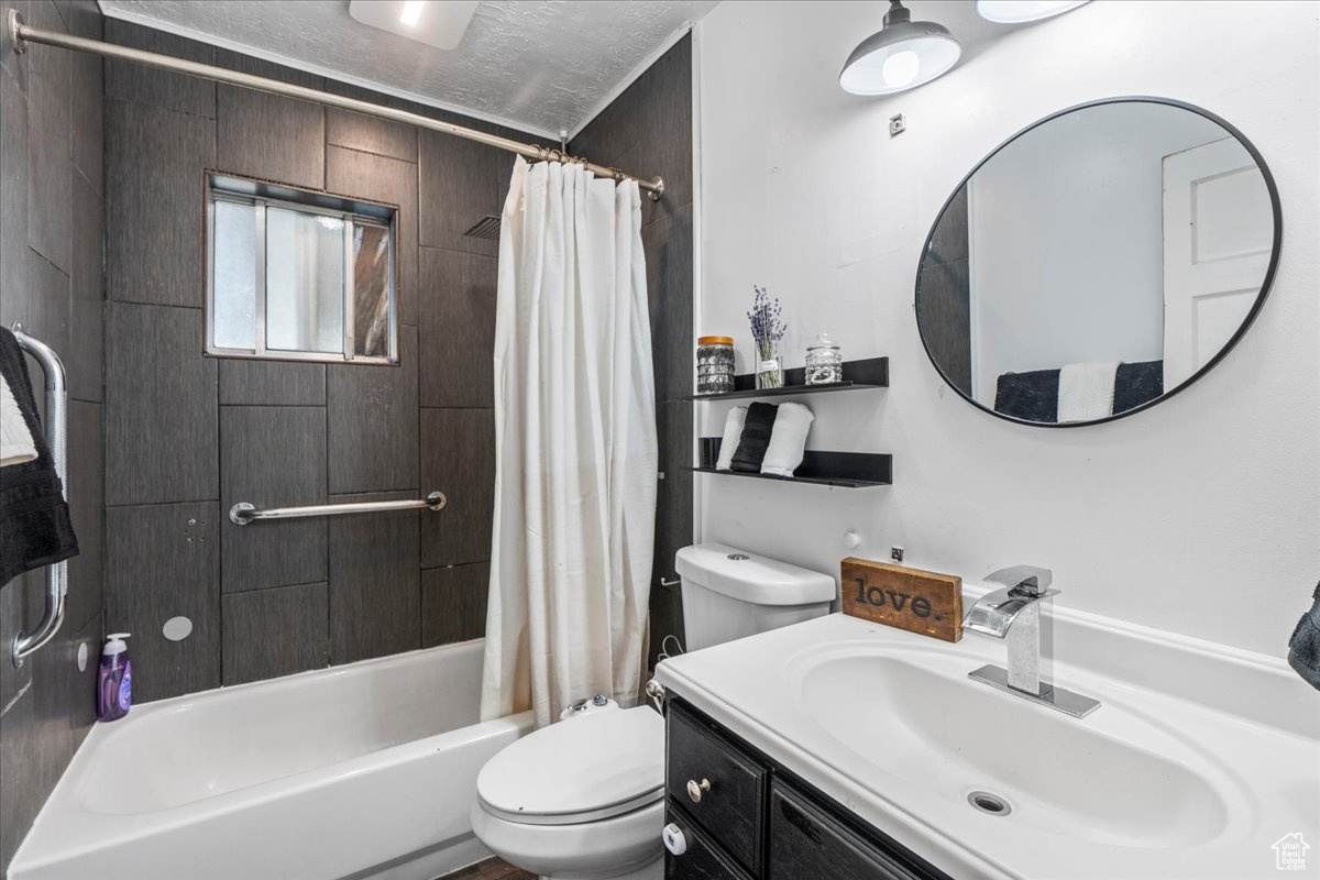 Full bathroom featuring vanity, shower / bath combo, a textured ceiling, and toilet