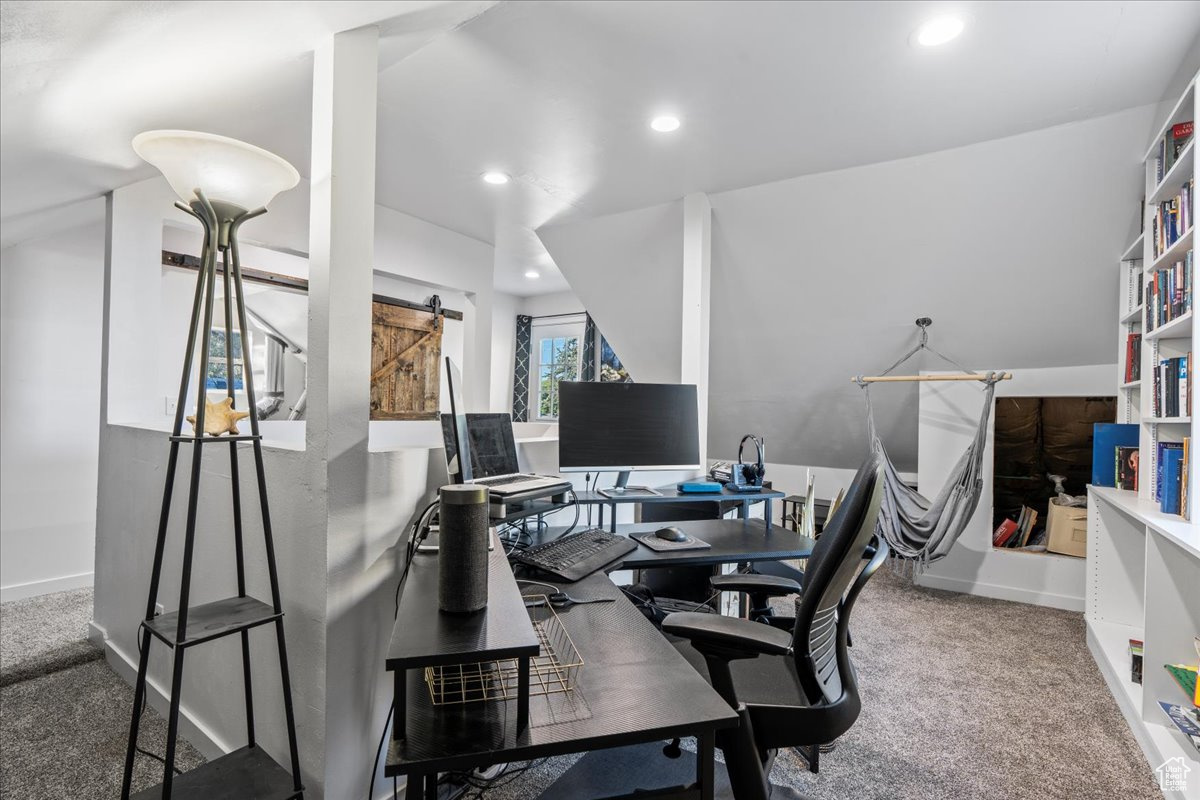 Carpeted office space with a barn door