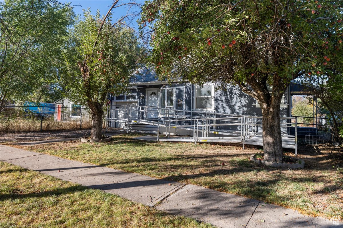 Obstructed view of property with a wooden deck and a front lawn