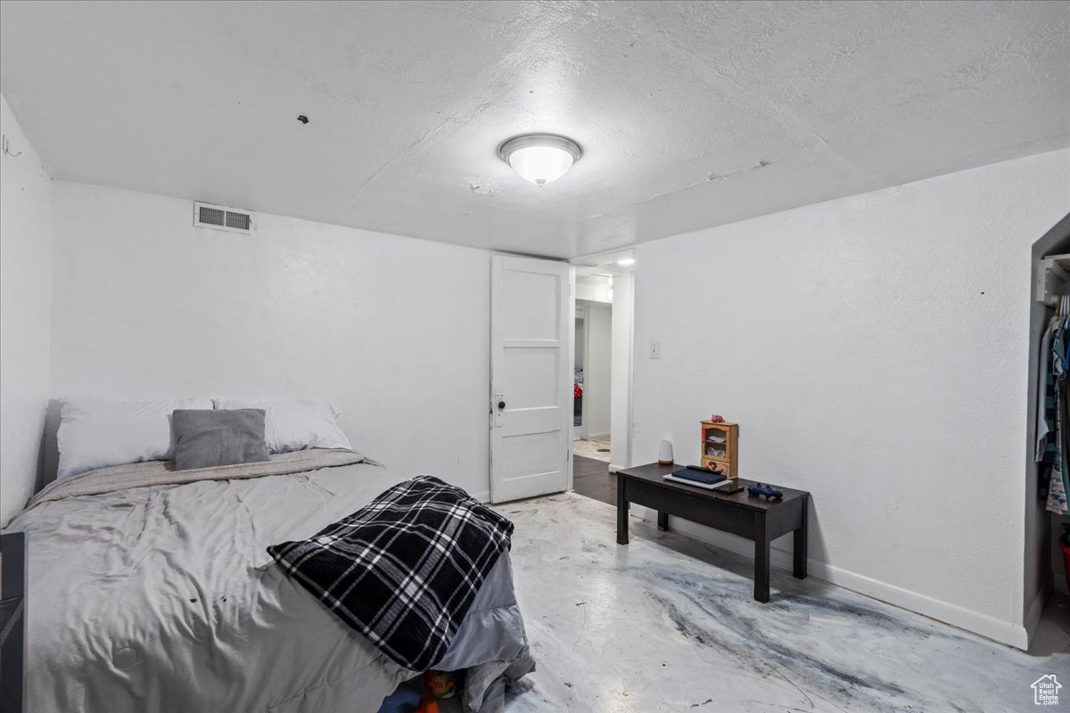 Bedroom with concrete floors and a textured ceiling