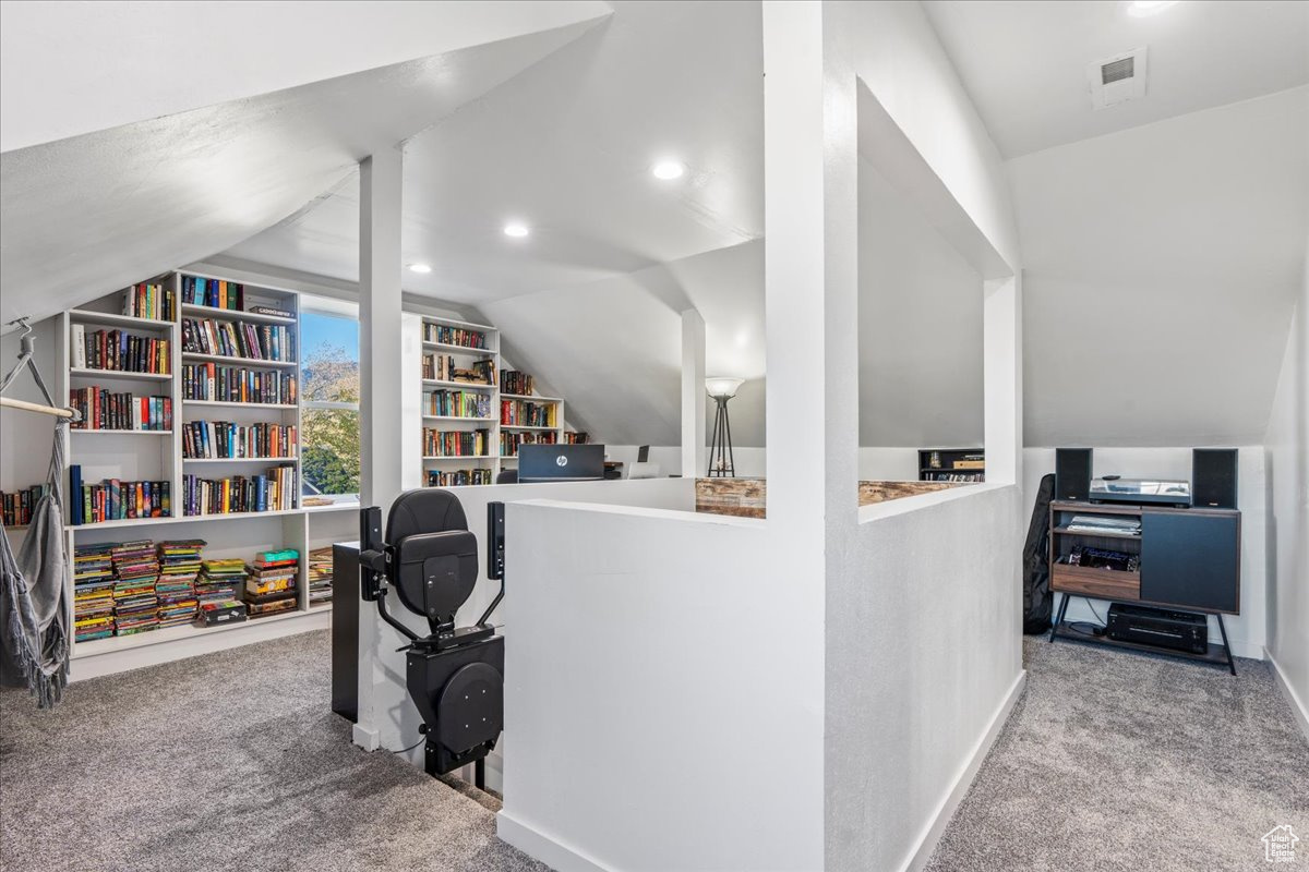 Home office with lofted ceiling and light carpet