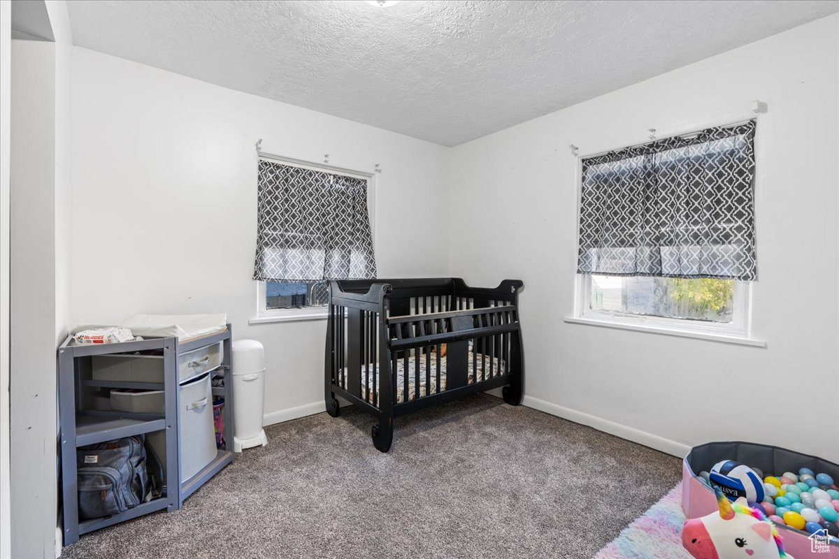 Carpeted bedroom with a nursery area and a textured ceiling