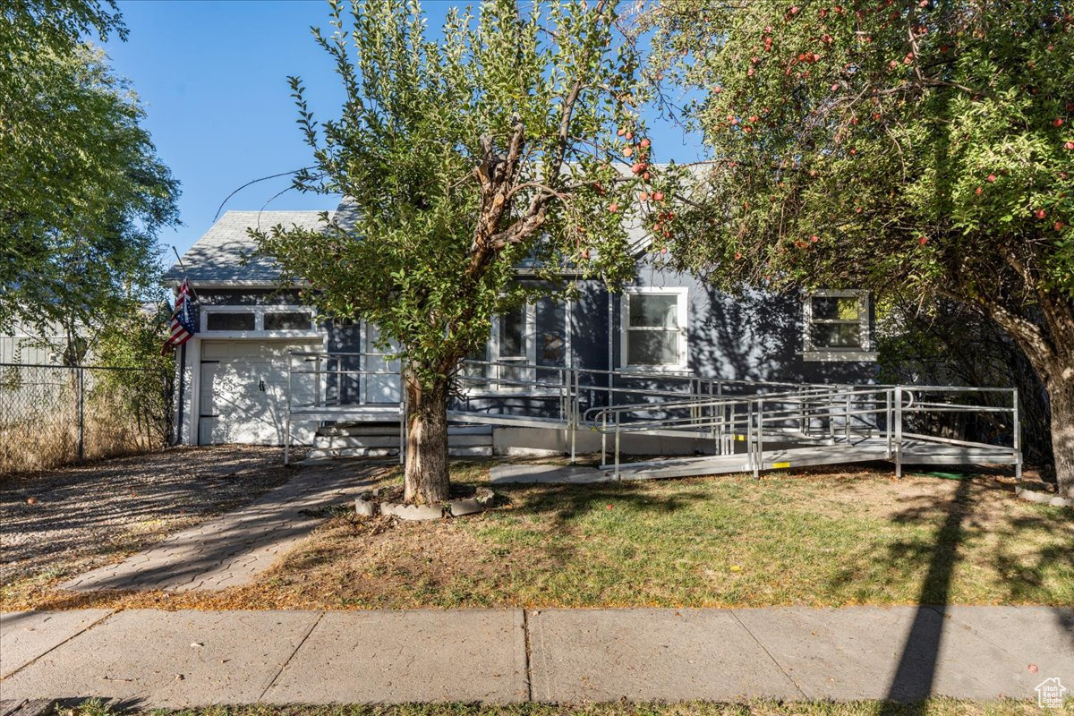 View of property hidden behind natural elements with a deck and a front lawn