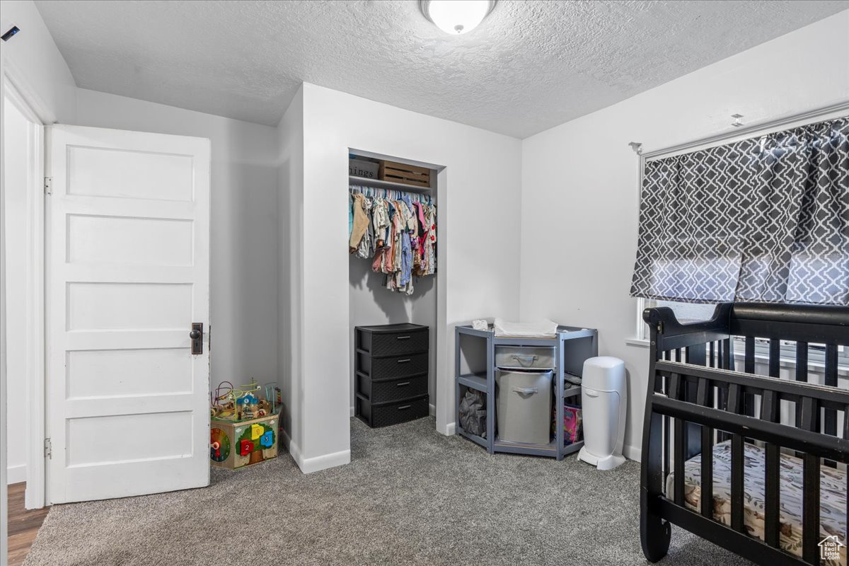 Bedroom with a textured ceiling, carpet floors, and a closet