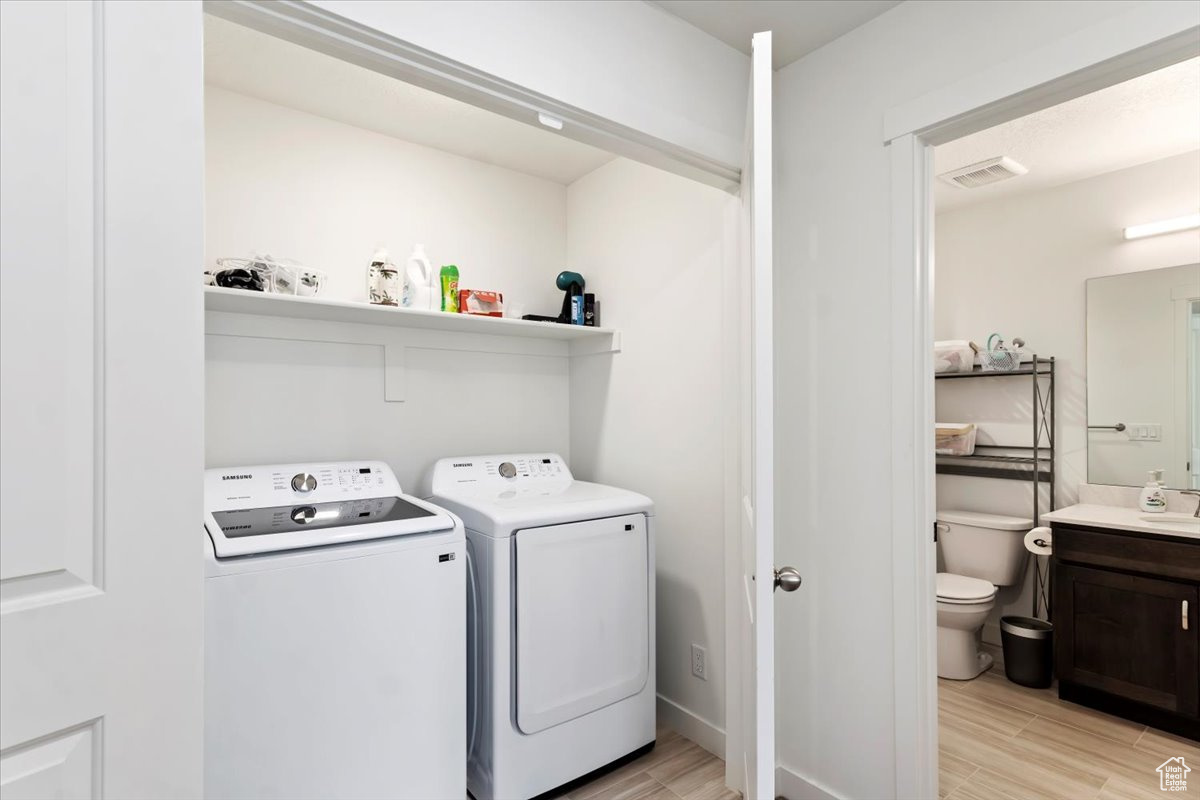 Washroom with independent washer and dryer and light wood-type flooring