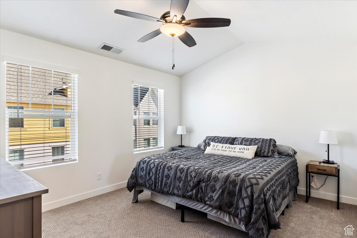 Bedroom featuring ceiling fan, light carpet, and vaulted ceiling