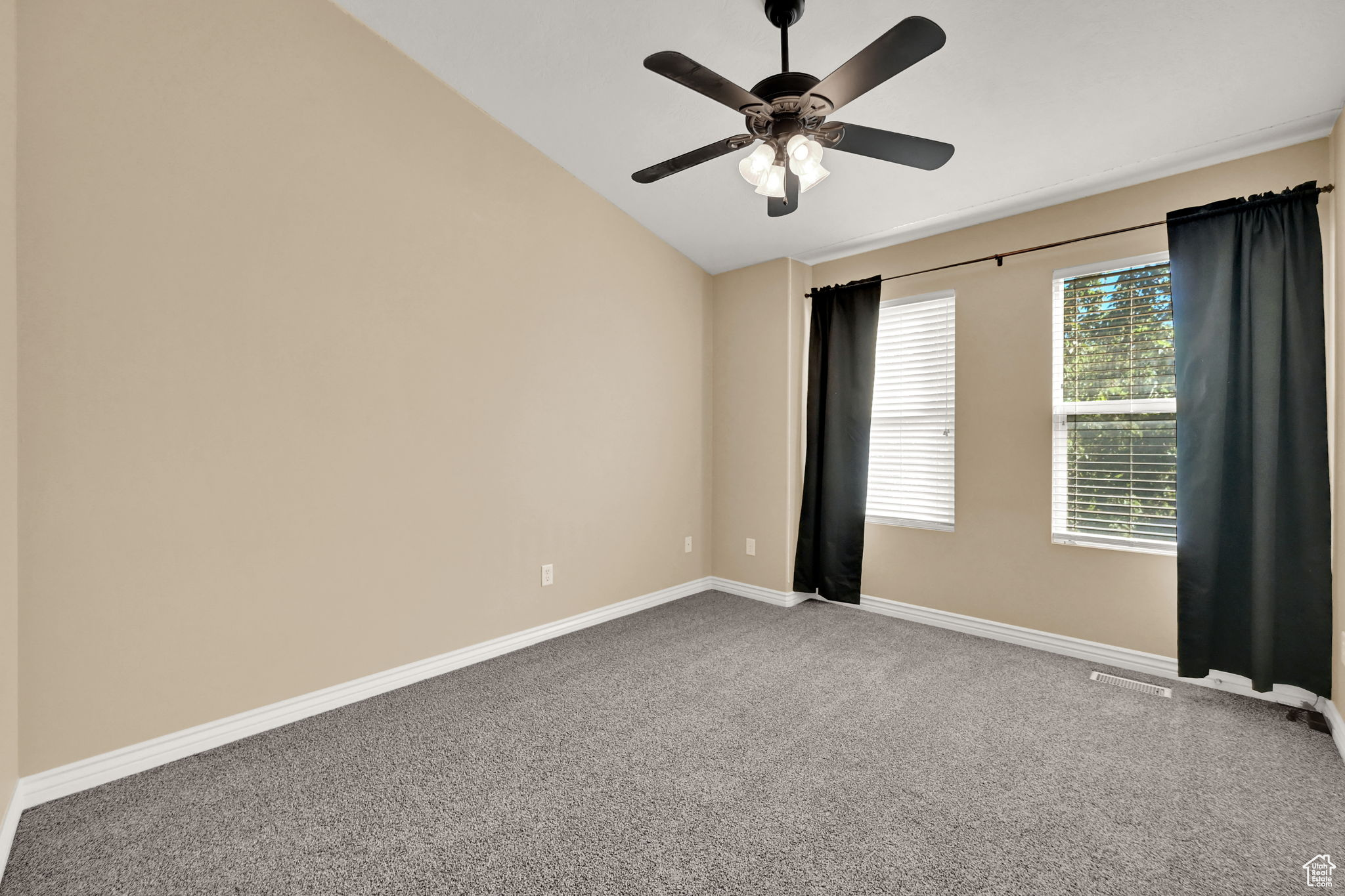 Carpeted empty room with vaulted ceiling and ceiling fan