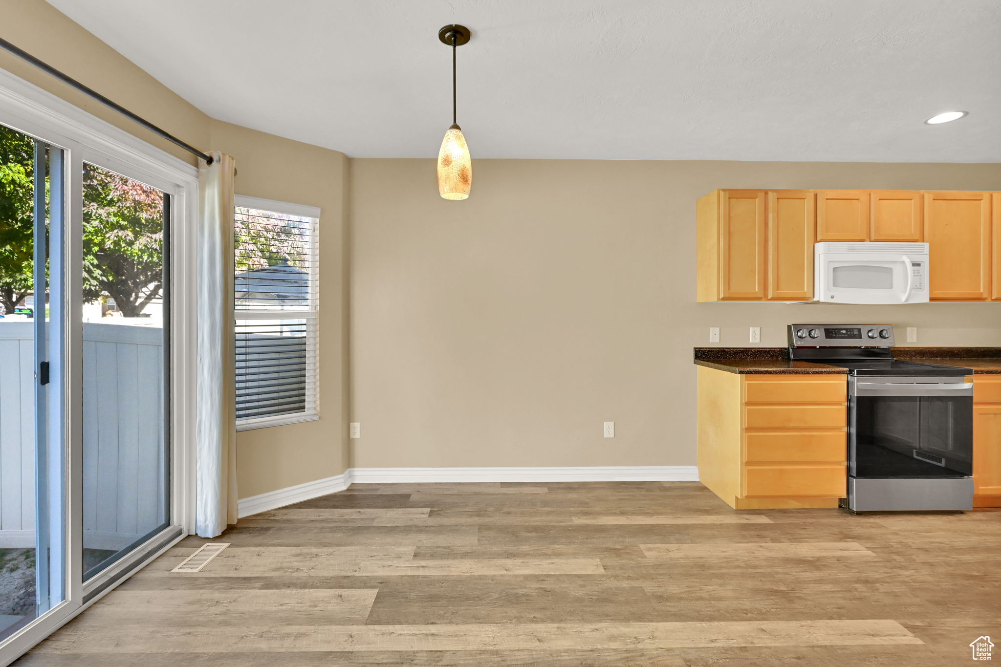 Kitchen featuring light hardwood / wood-style flooring, light brown cabinetry, stainless steel electric range oven, and pendant lighting