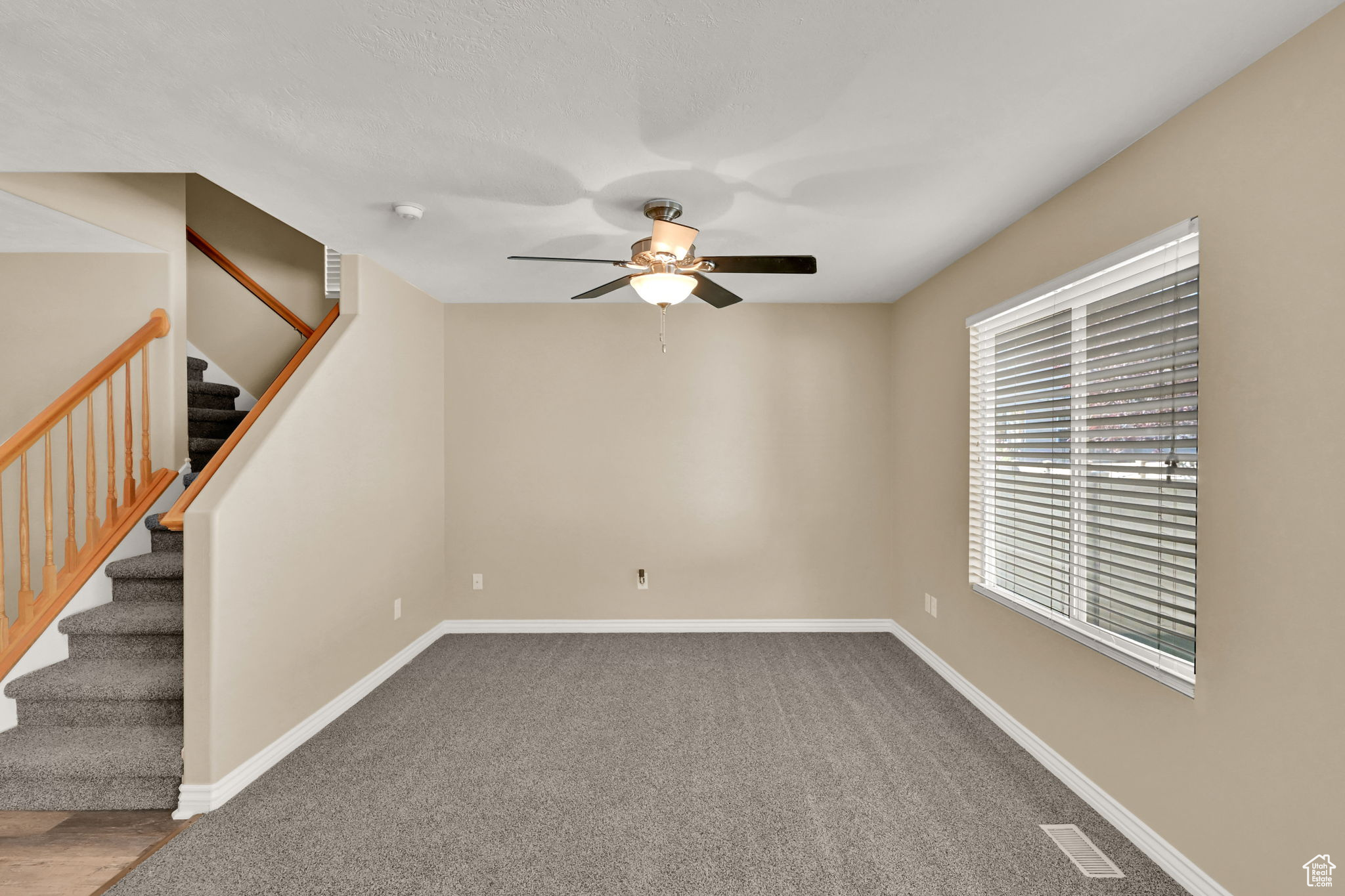 Carpeted spare room with ceiling fan