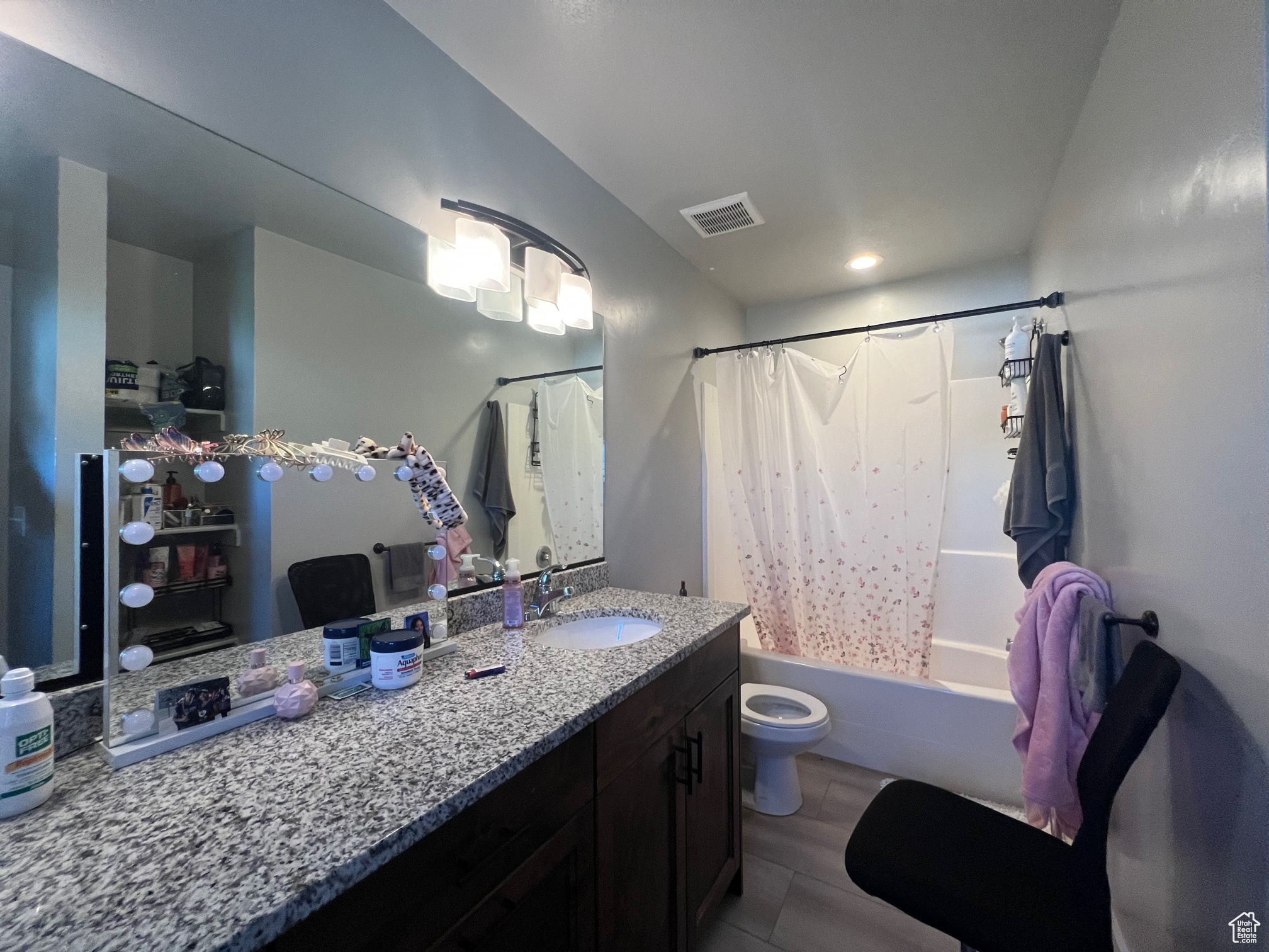 Full bathroom with toilet, hardwood / wood-style flooring, shower / bathtub combination with curtain, and vanity