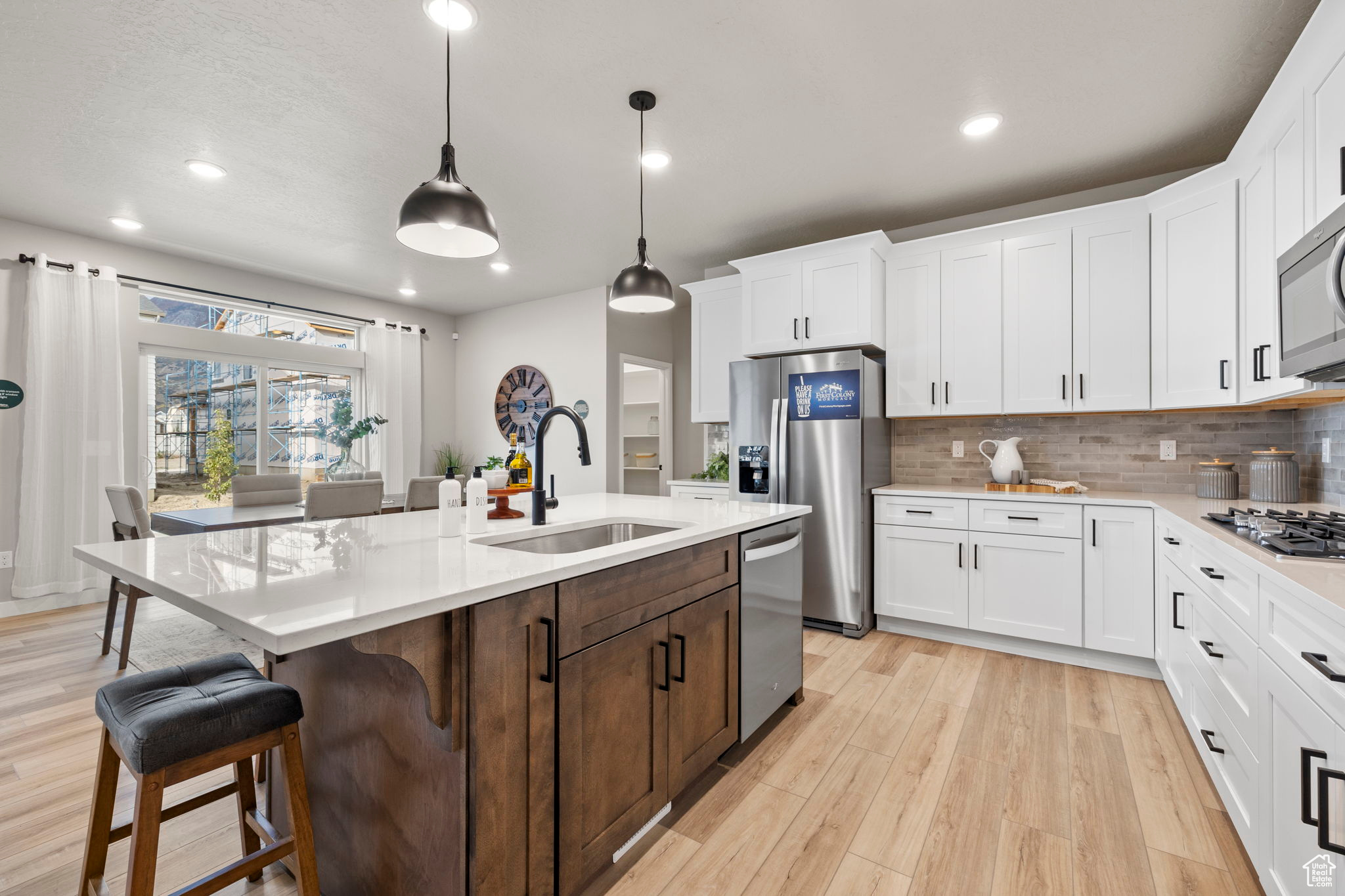 Kitchen with white cabinetry, stainless steel appliances, sink, and a center island with sink